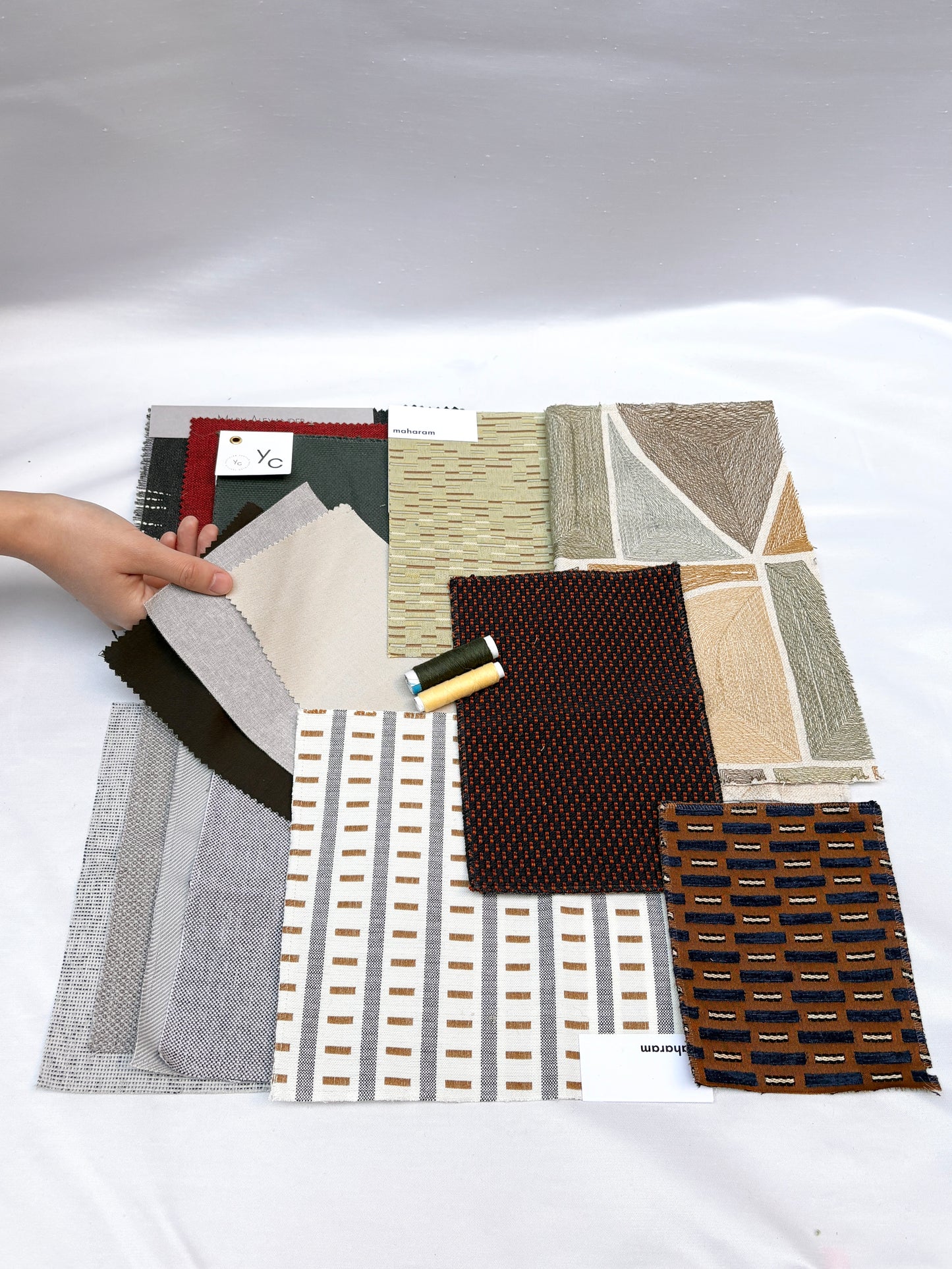 Mixed fabric swatches in varied patterns and textures with matching thread spools.