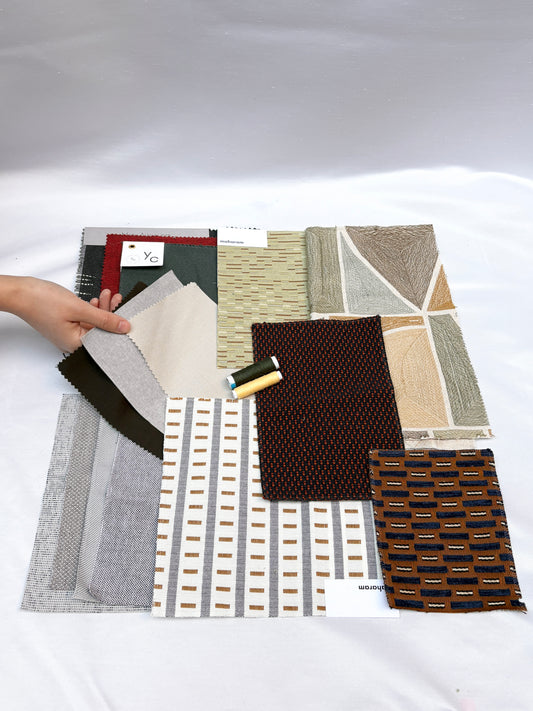 Mixed fabric swatches in varied patterns and textures with matching thread spools.