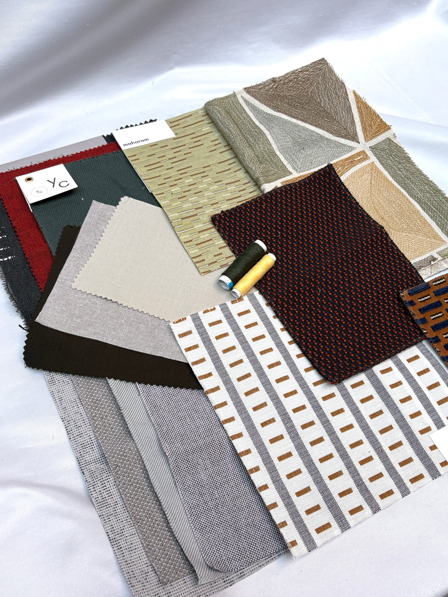 Patterned fabric swatches in mixed textures with coordinating thread spools.