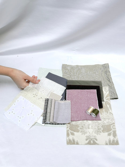 Fabric swatches in mixed textures with thread spools and lace details.