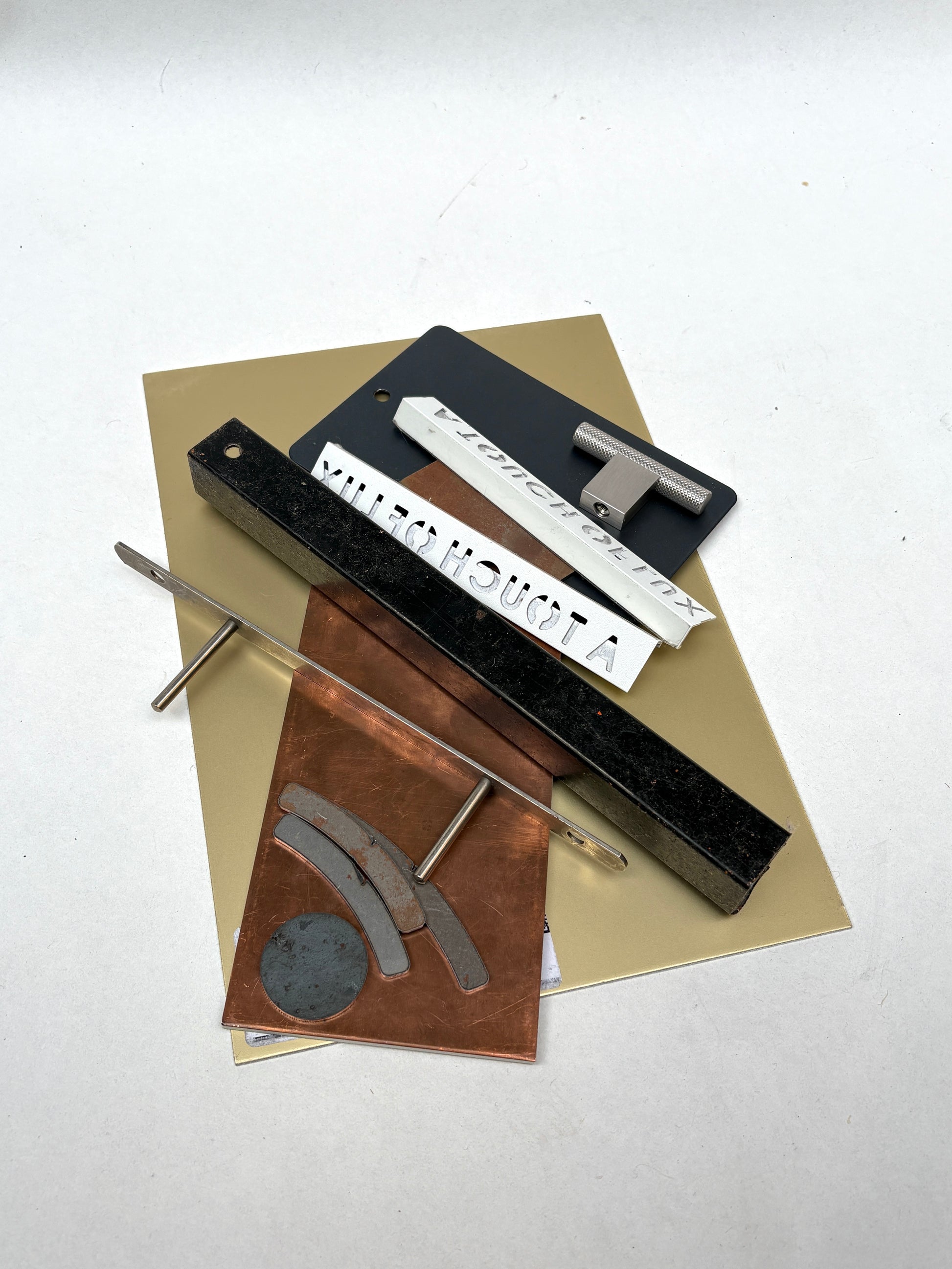 Assorted metal offcuts and hardware pieces sit on a white surface