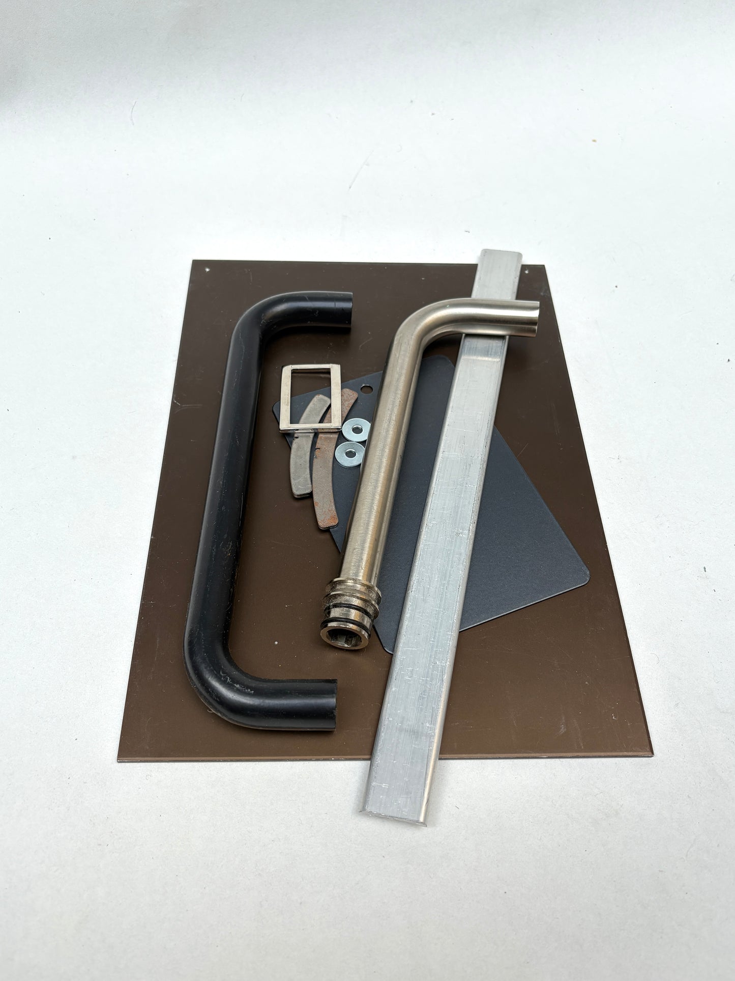 Flat and curved metal pieces are grouped on a white background