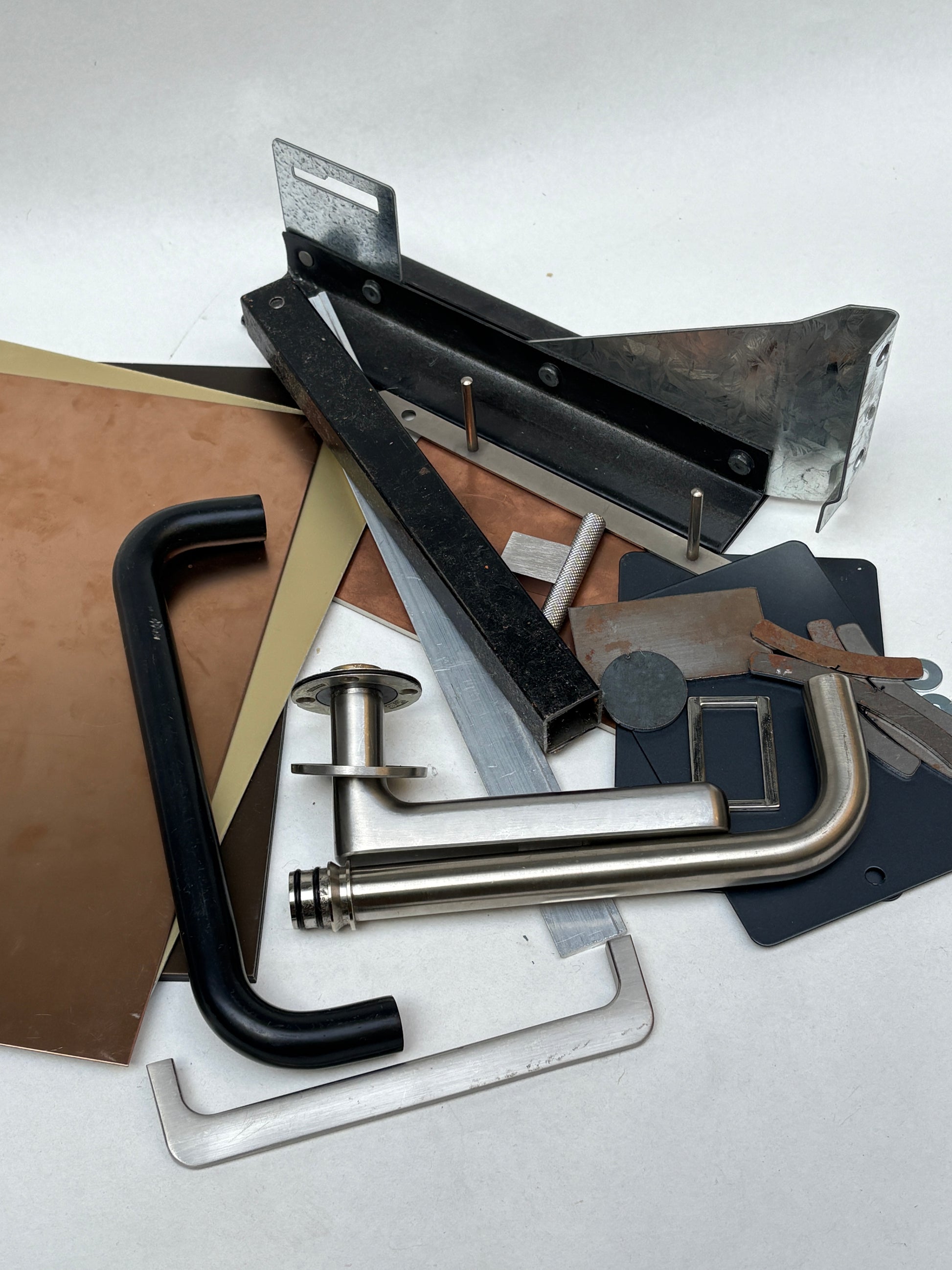 Flat and curved metal pieces are grouped on a white background