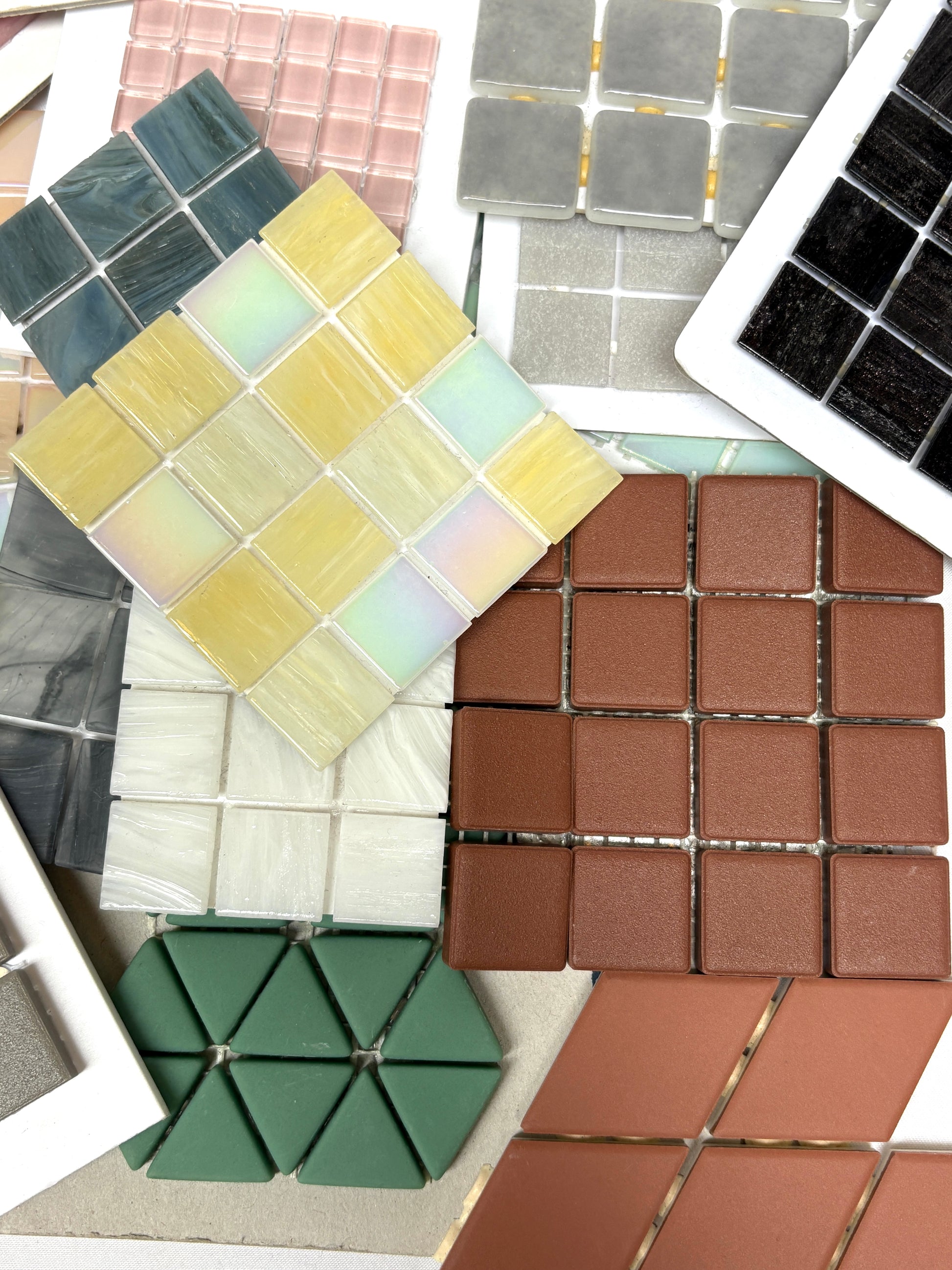 Mixed mosaic tile sheets are arranged in overlapping layers on white