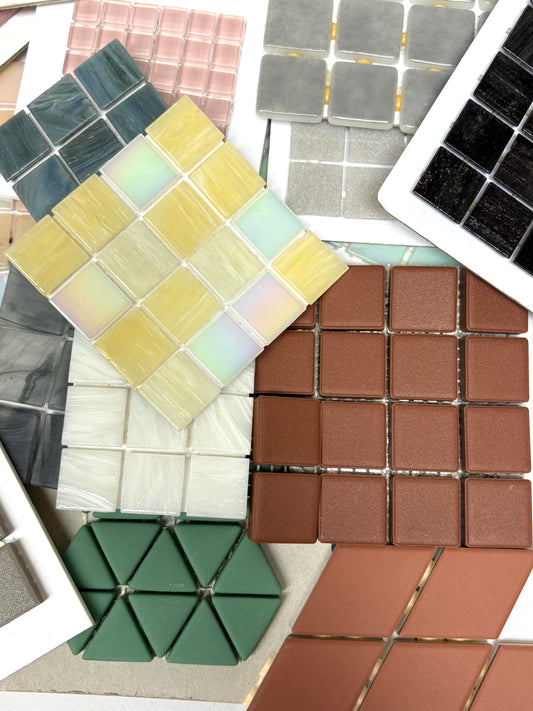 Mixed mosaic tile sheets are arranged in overlapping layers on white