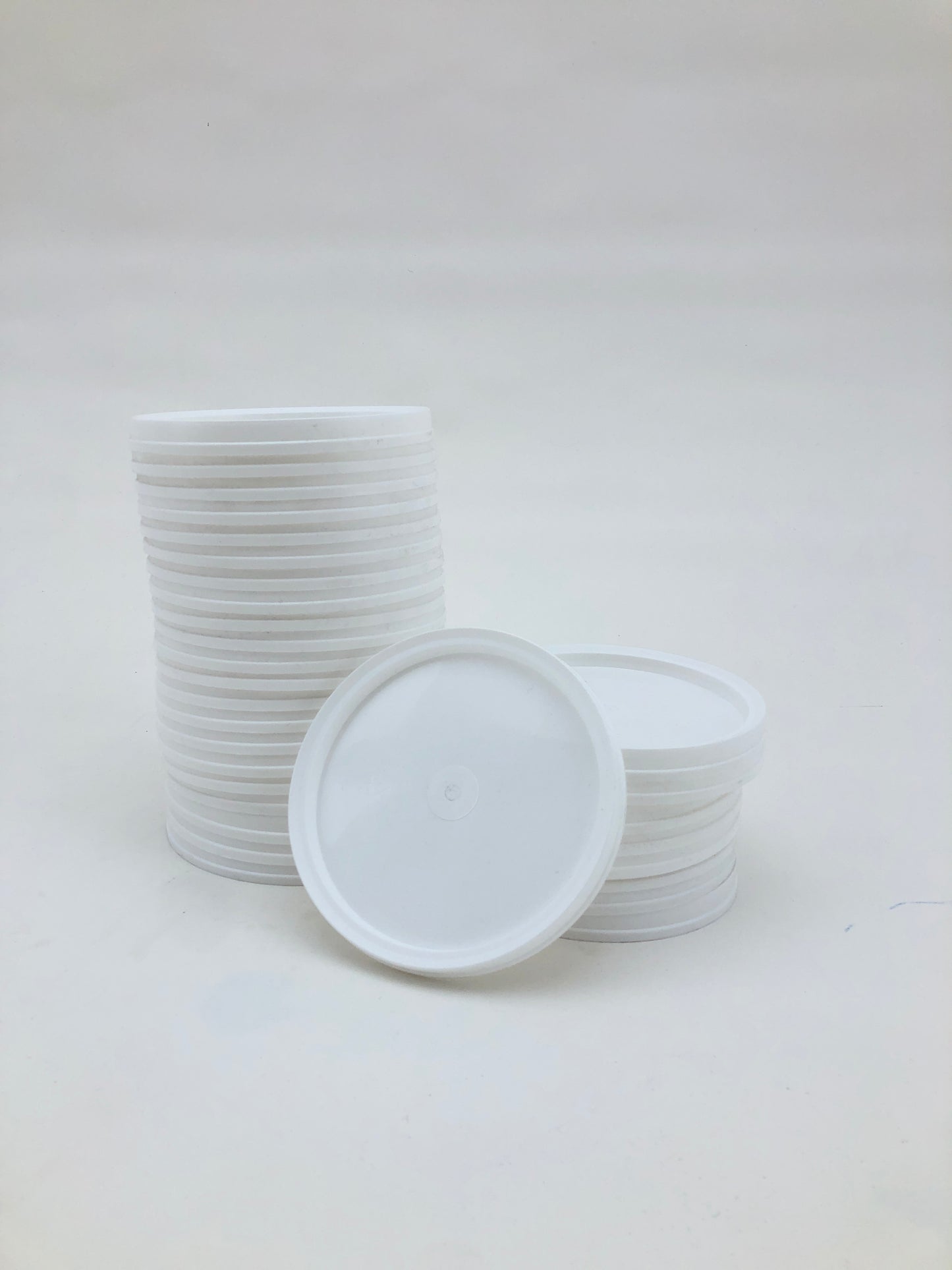 White plastic paint palettes are stacked on a white background