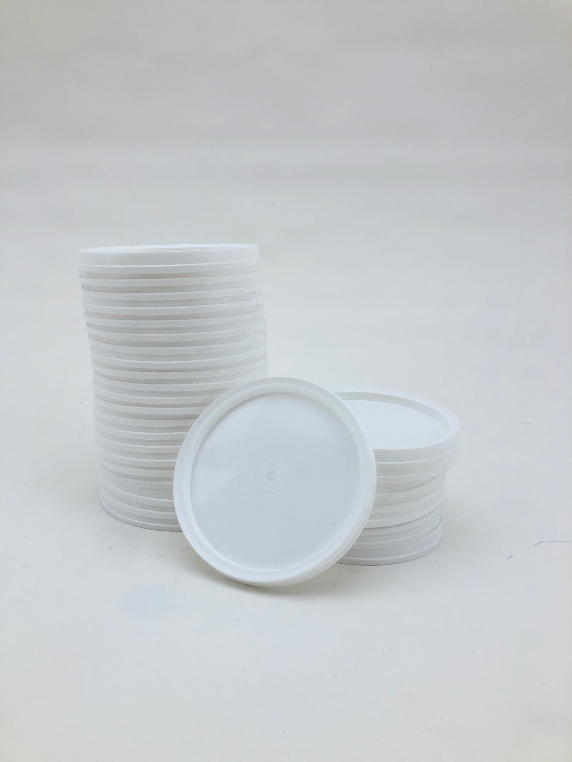 White plastic paint palettes are stacked on a white background