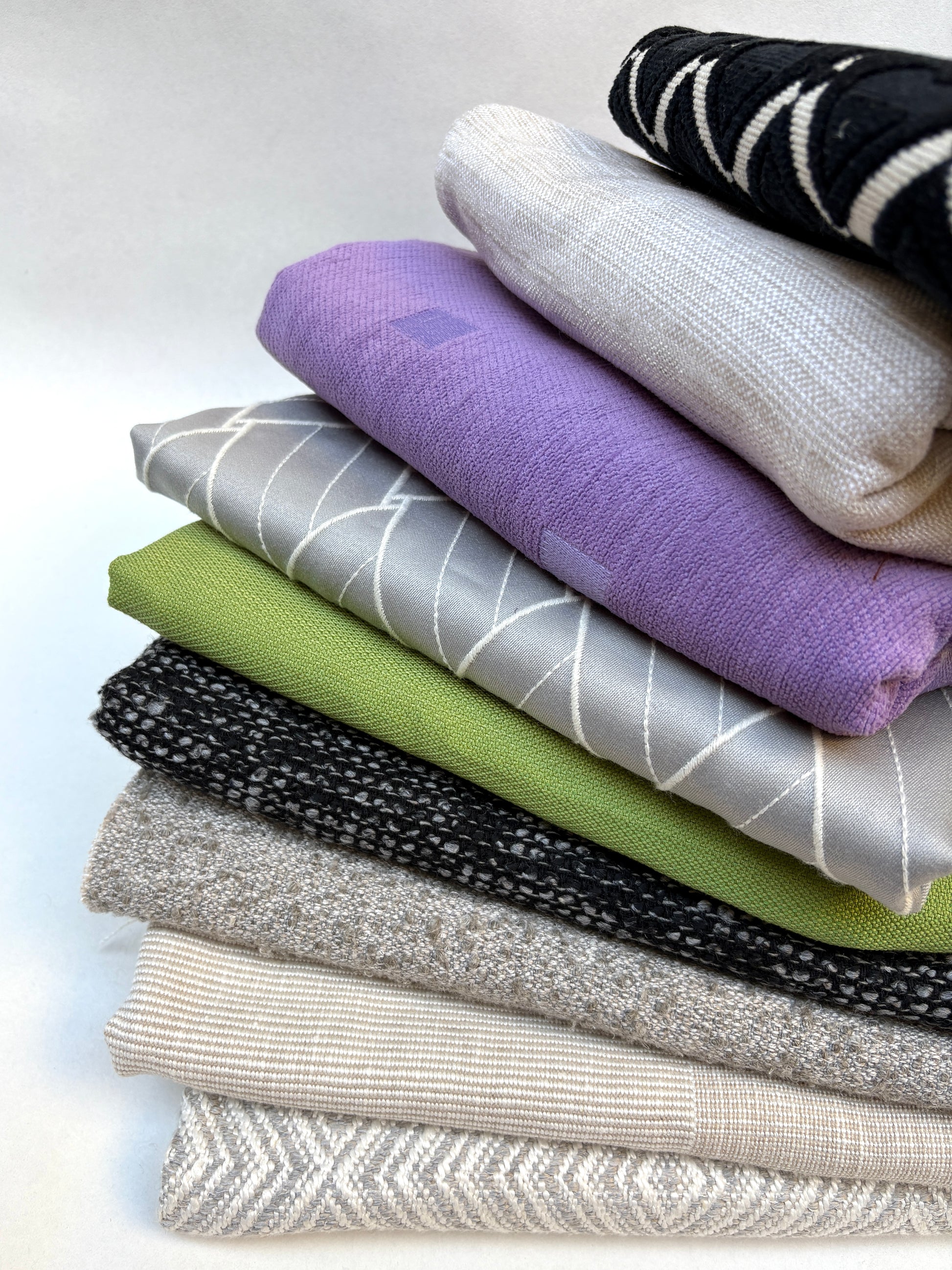 Stack of mixed patterned upholstery fabric pieces photographed on a white background.