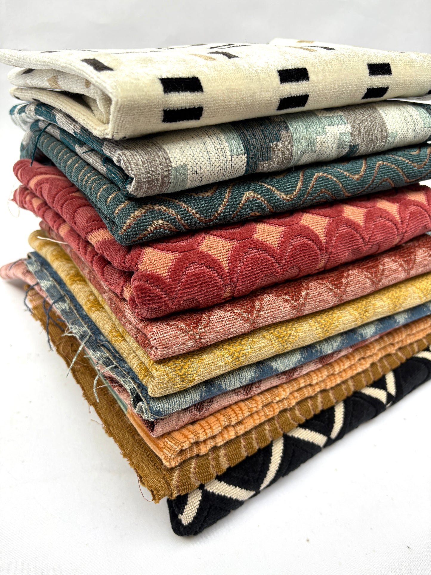Stack of folded patterned fabric swatches with various patterns and colours 