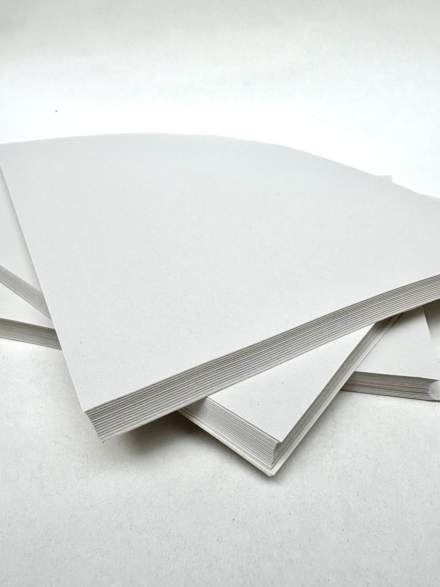 A stack of white paper sheets rests on a white surface
