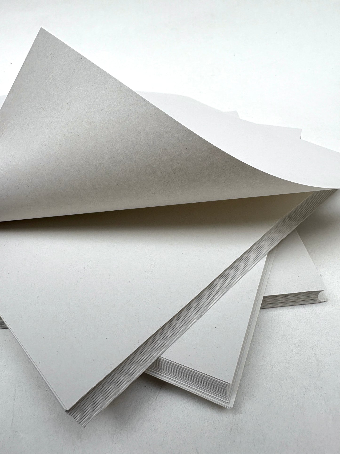 Thin white paper sheets are layered with one page lifted