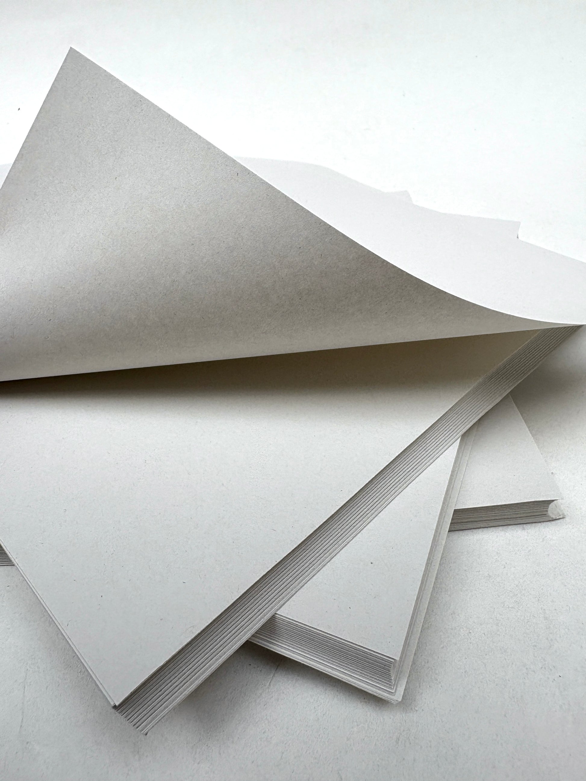 Thin white paper sheets are layered with one page lifted