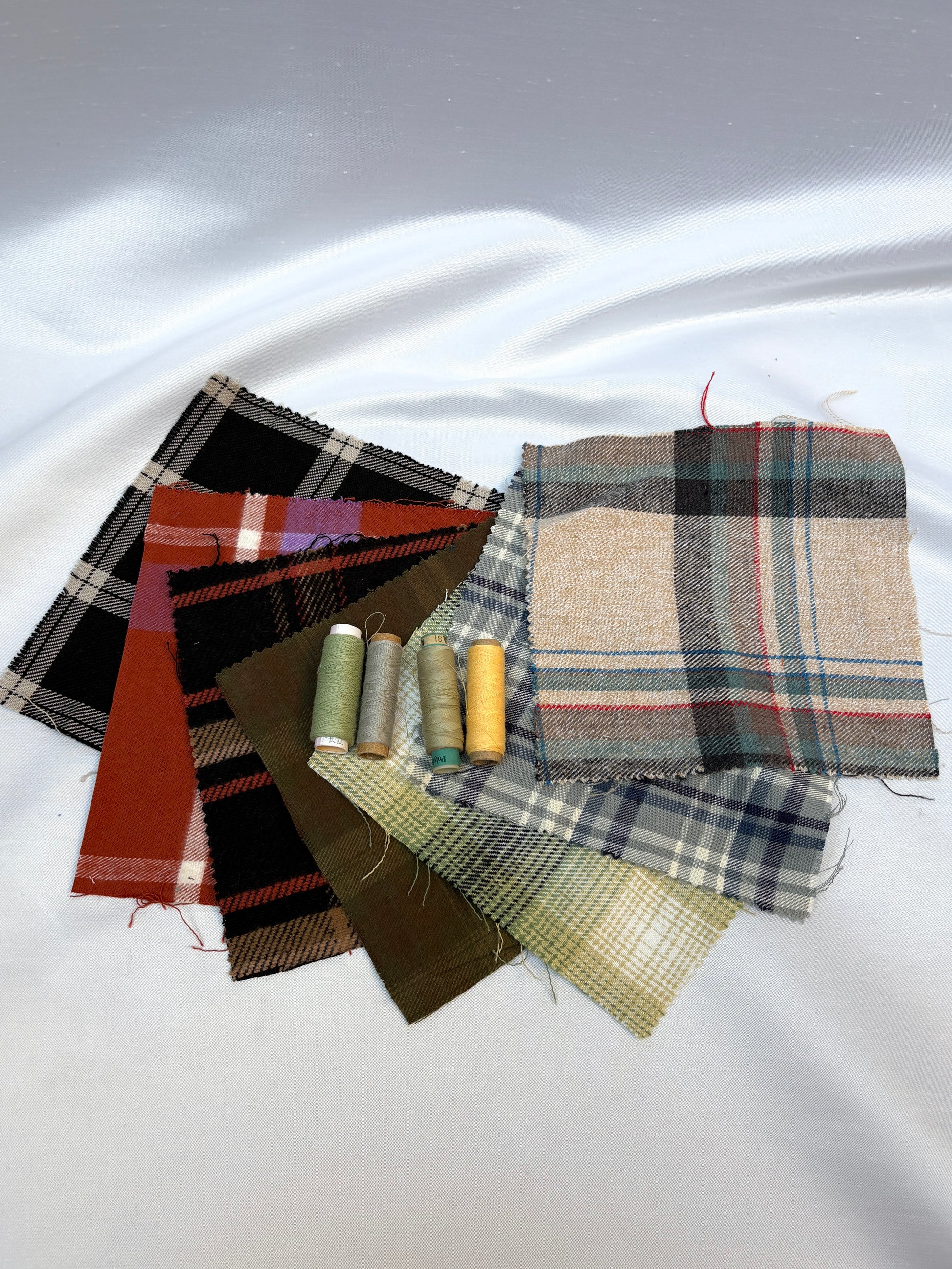 Checked fabric swatches with coordinating thread spools on white fabric.