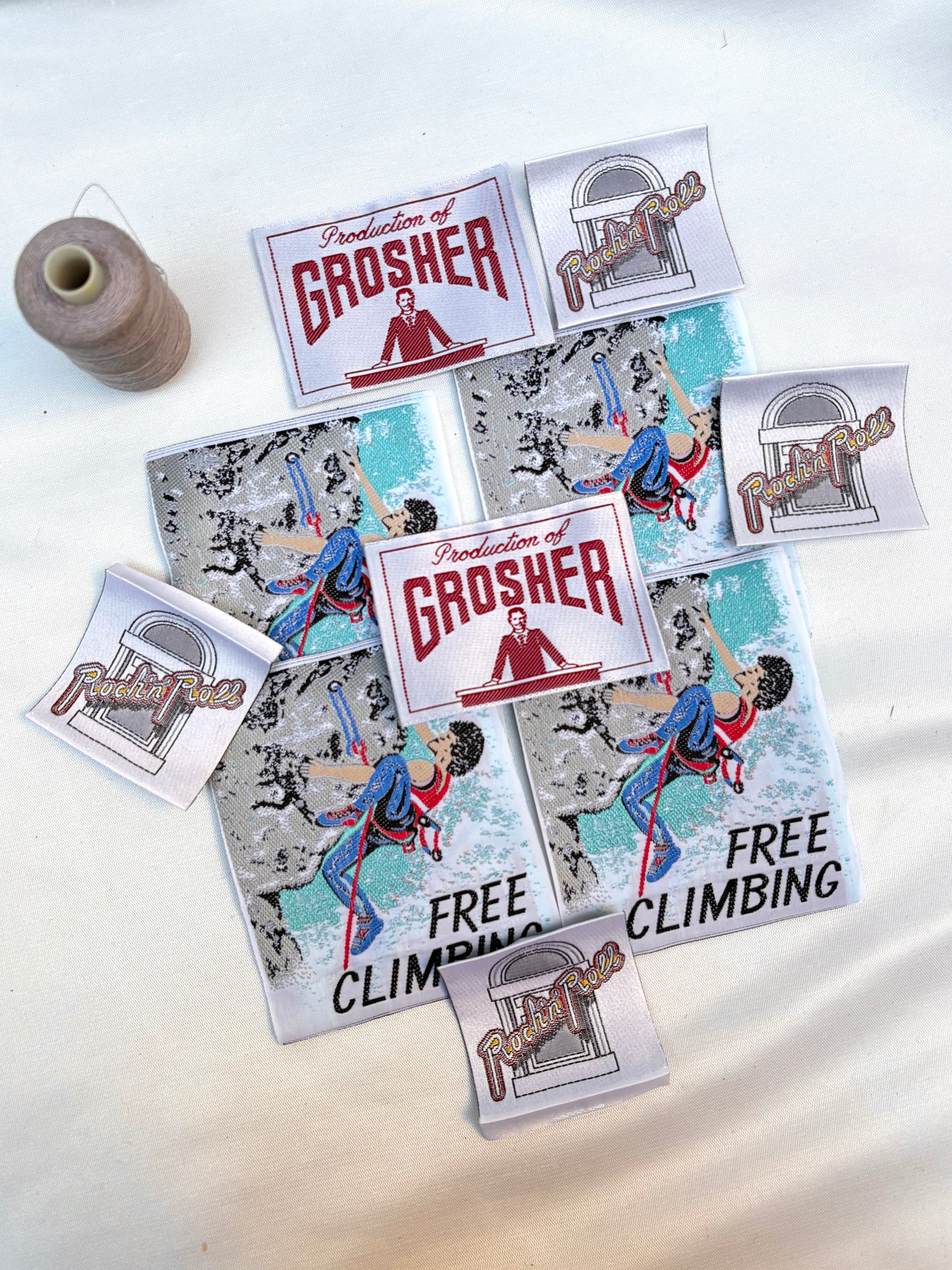Assorted woven labels and climbing badges displayed beside a thread spool.