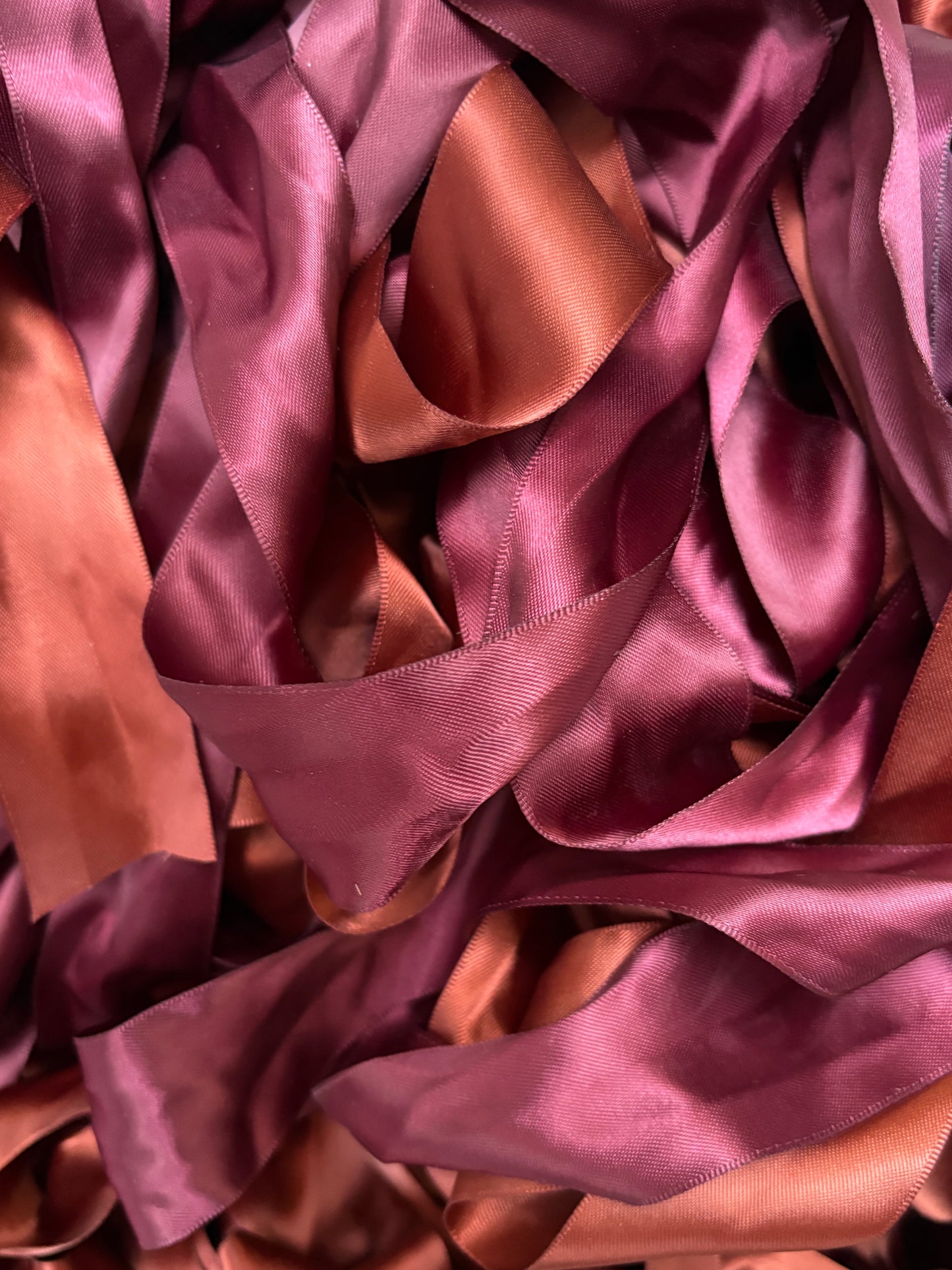 Satin ribbon strips in pink and copper tones layered together.