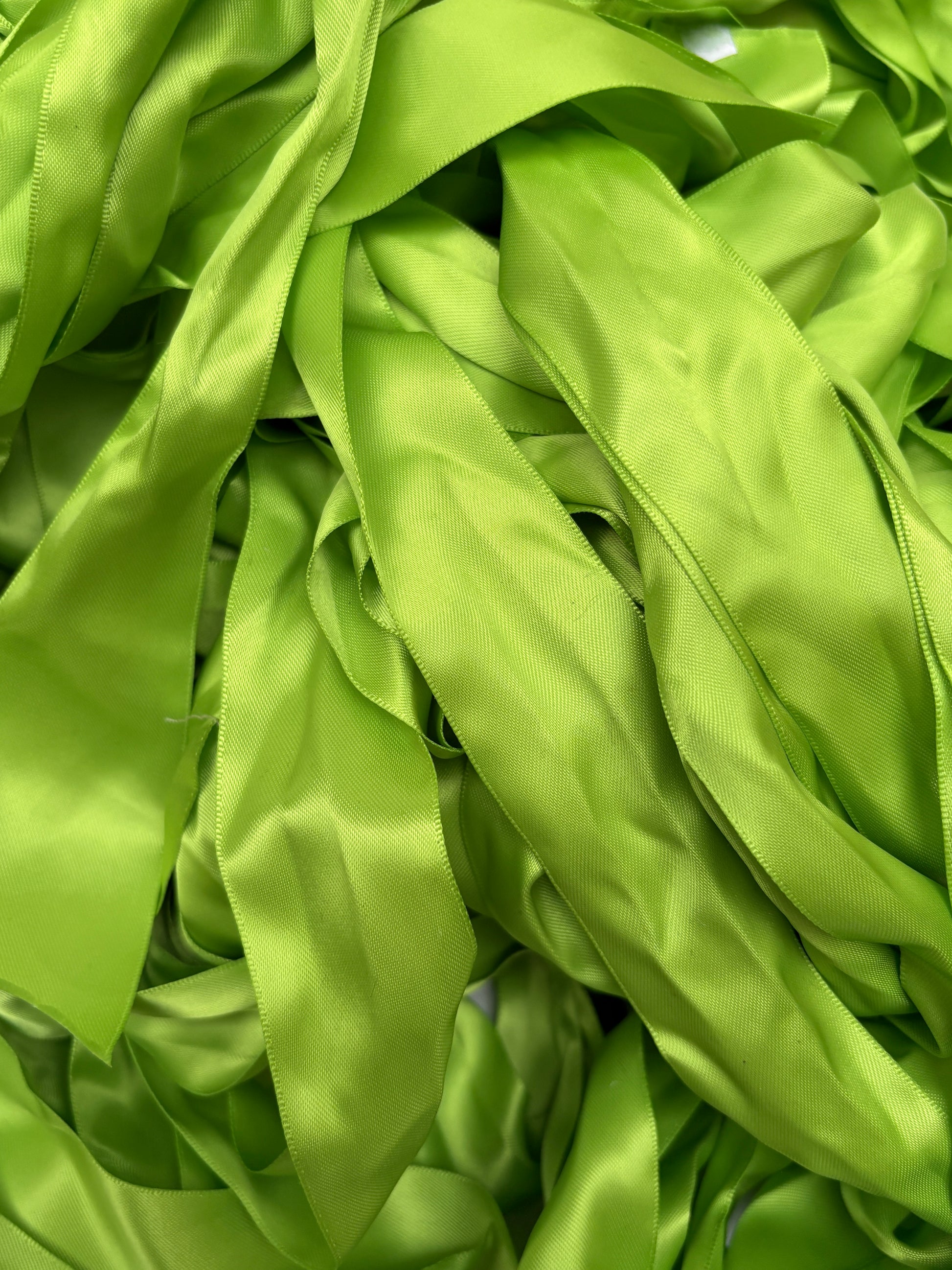 A pile of light green satin ribbons layered in soft folds.
