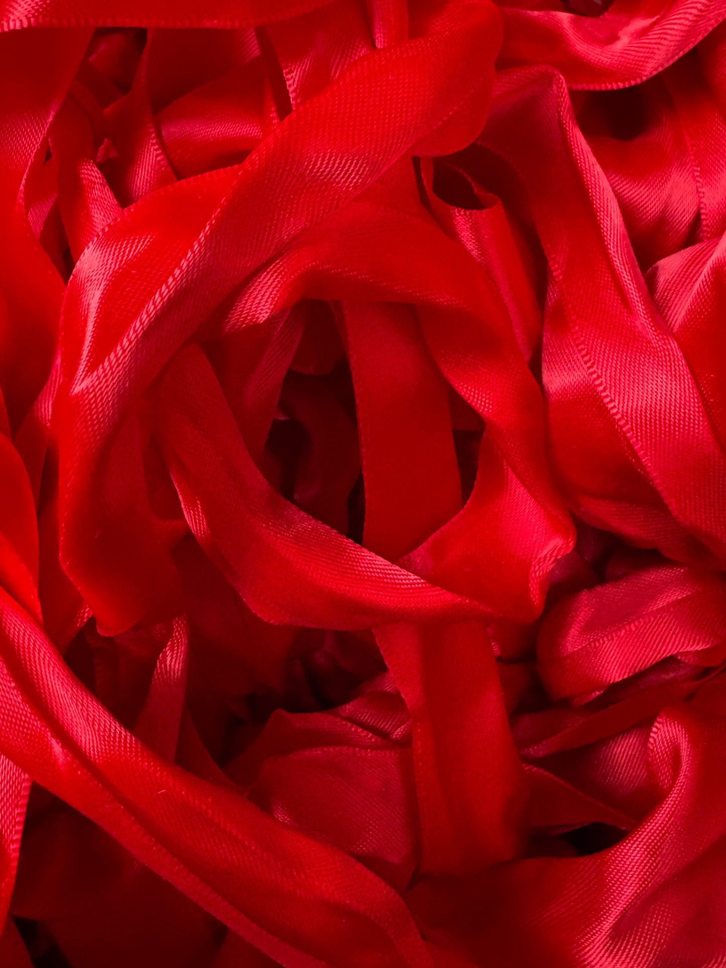 A pile of bright red satin ribbons layered in soft folds.