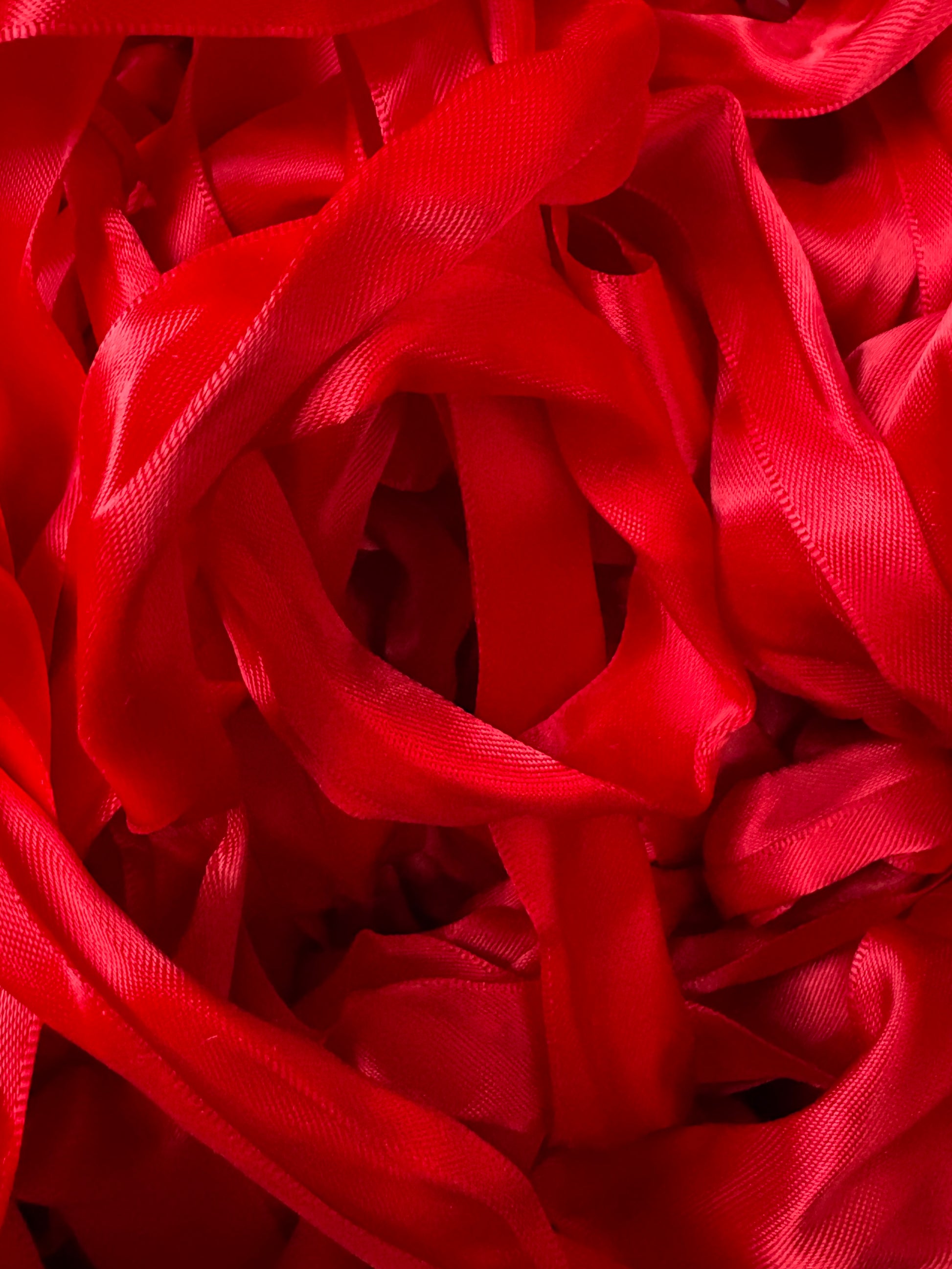 A pile of bright red satin ribbons layered in soft folds.