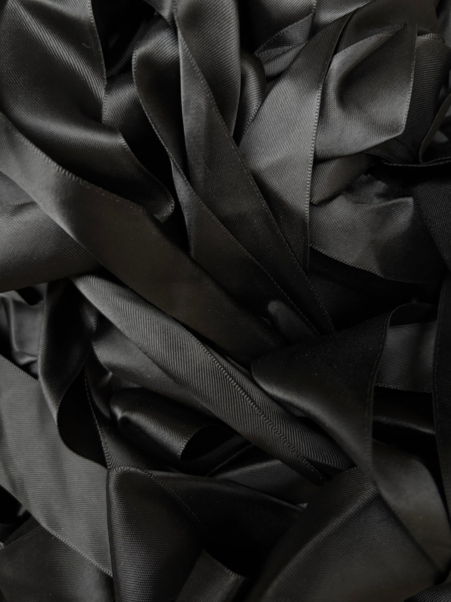 A pile of black satin ribbons layered in soft folds.