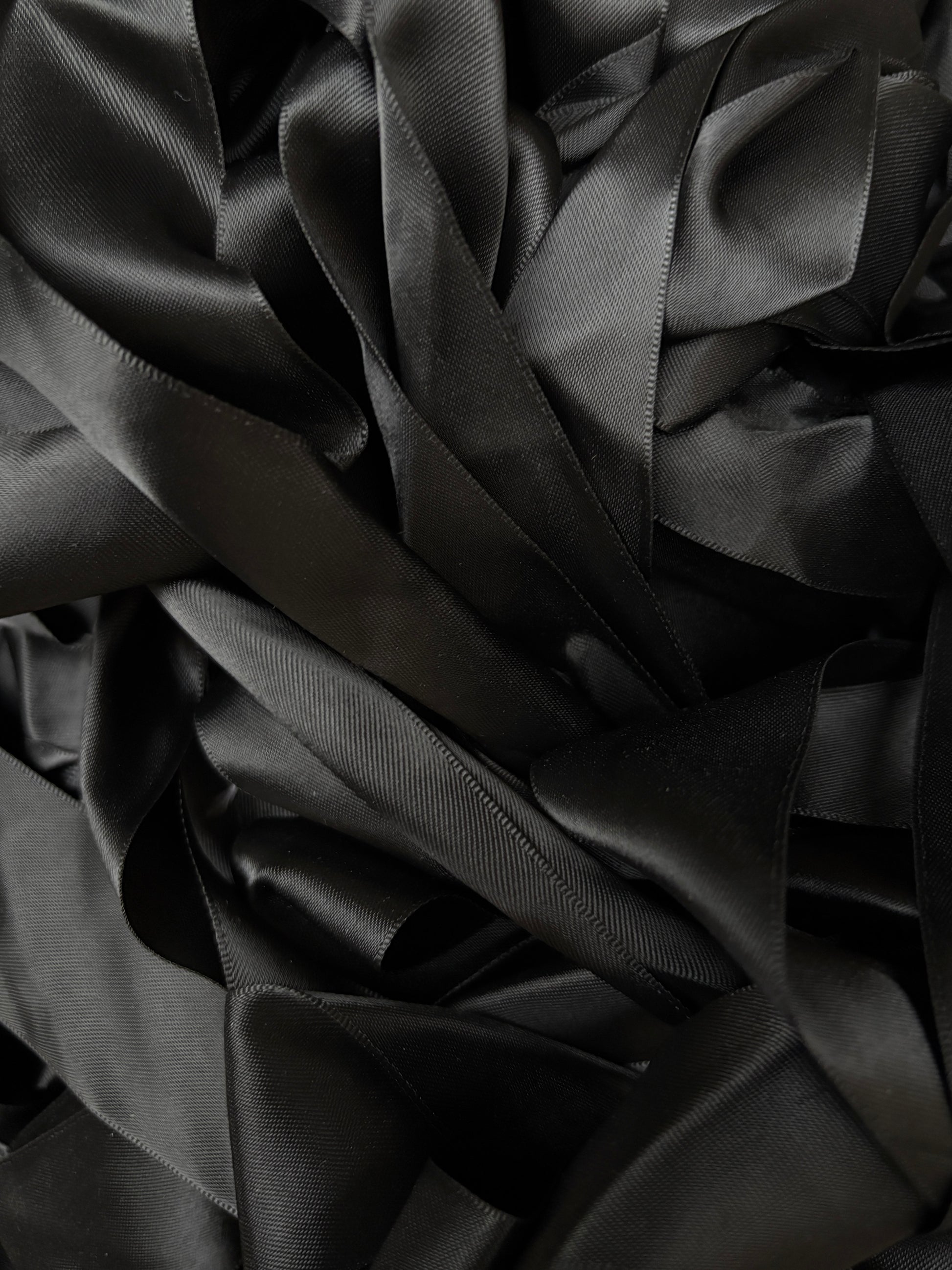 A pile of black satin ribbons layered in soft folds.