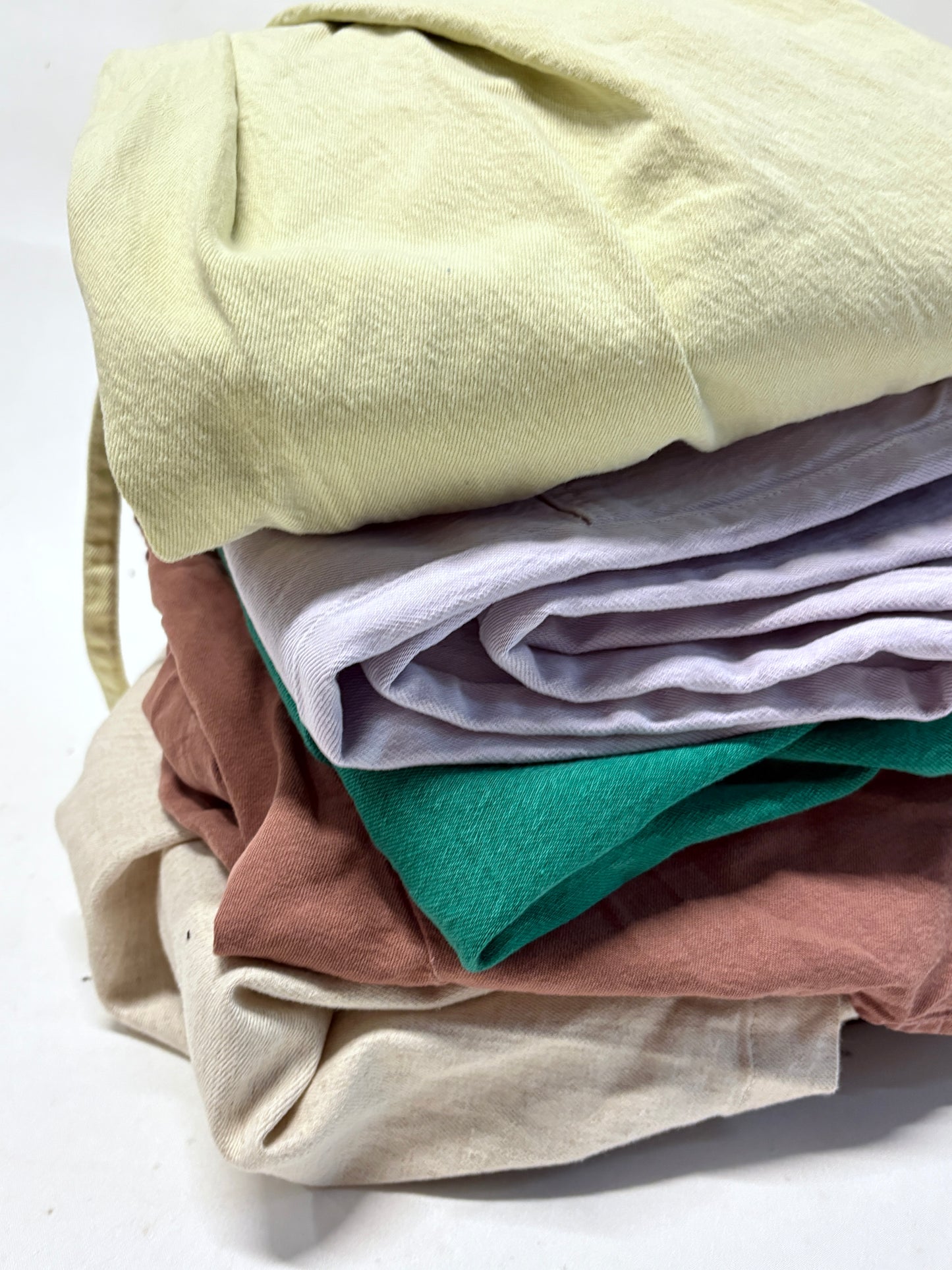 Stack of folded colourful ripped denim garments 