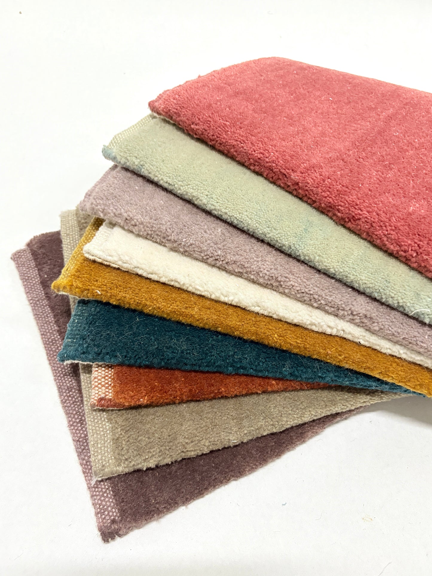 Stacked velvet fabric swatches in assorted colours and soft textures.