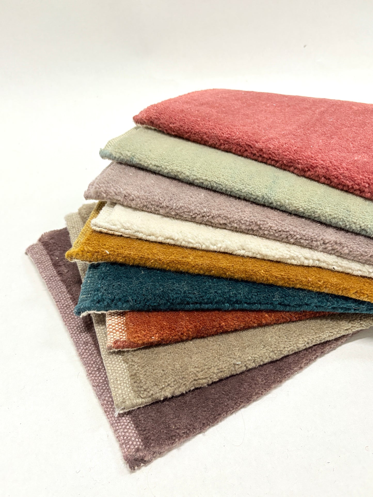 Layered velvet fabric swatches in assorted colours with soft, plush textures.