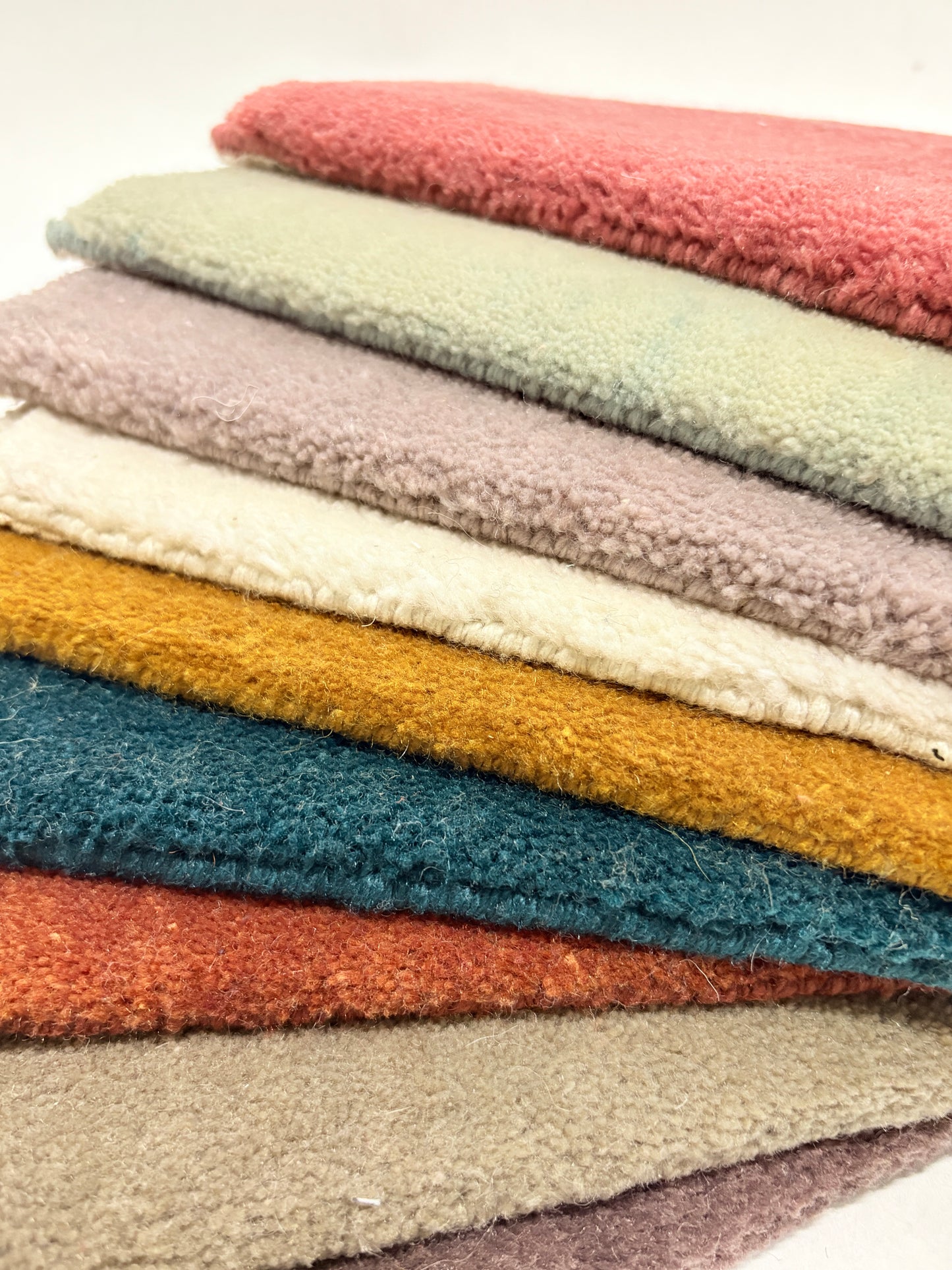 Close-up shots of multi-layered velvet fabric samples in various colors and with a soft, fluffy texture.