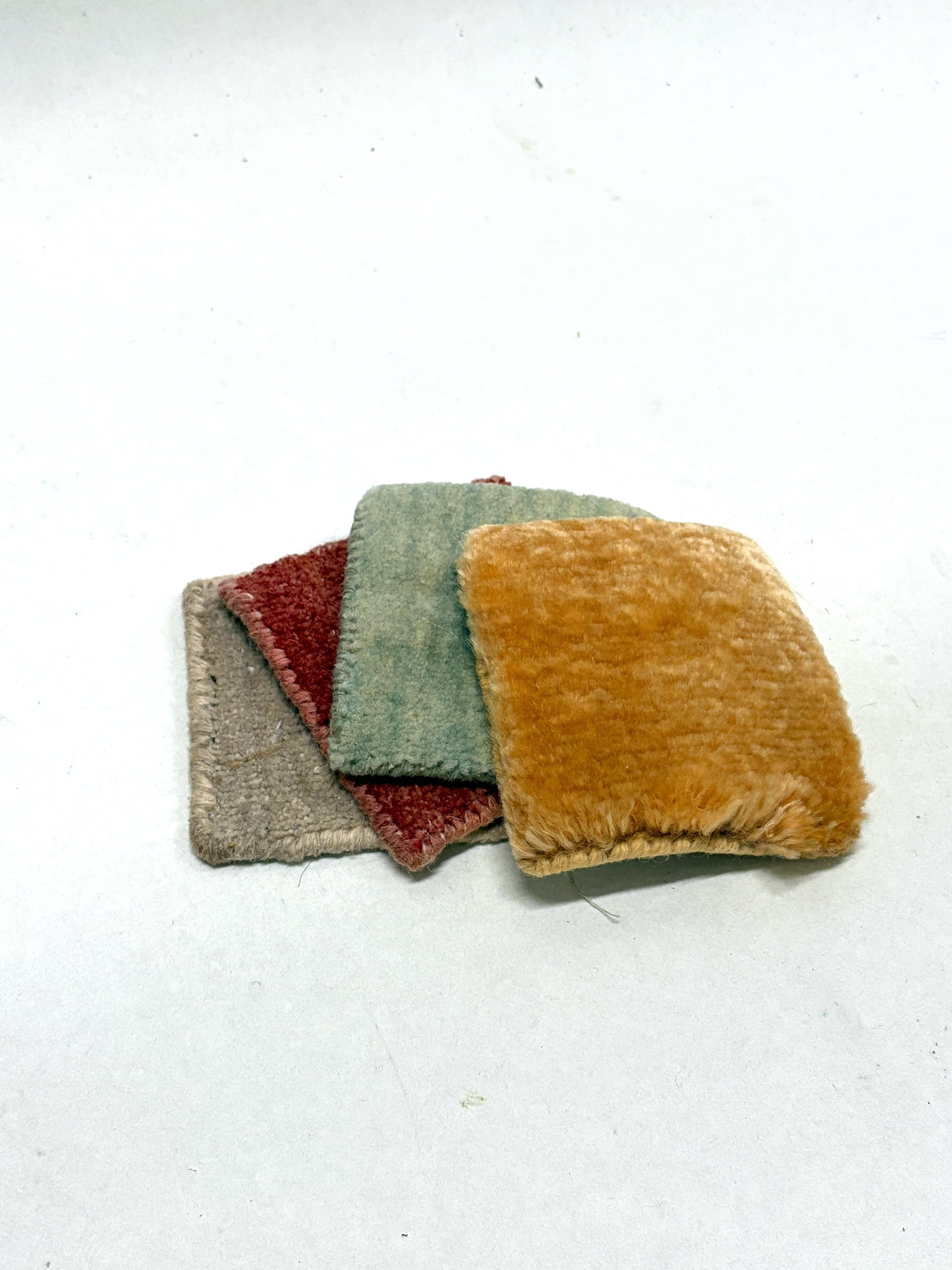 Stacked velvet fabric swatches in soft muted colours on white.