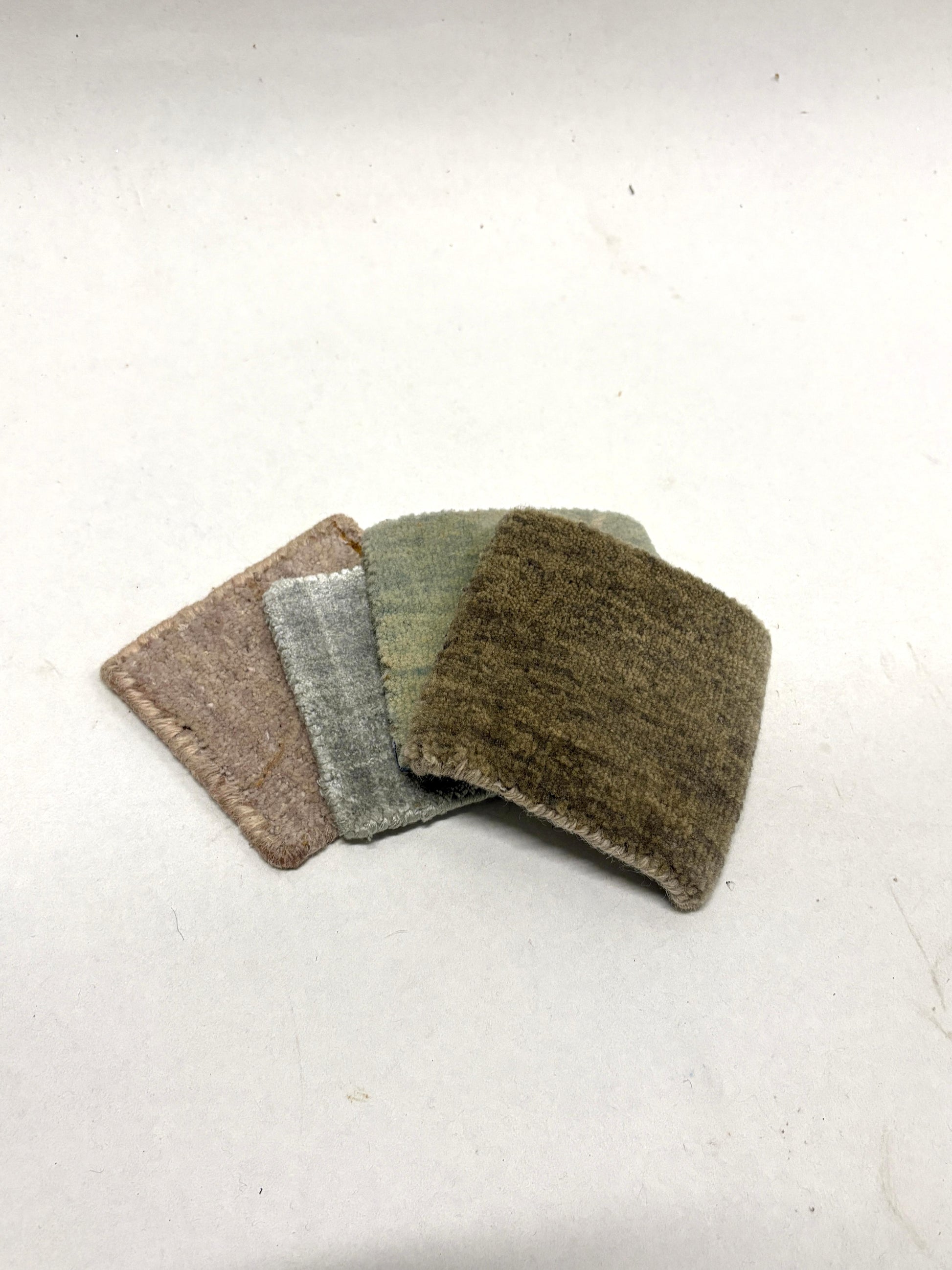 Stacked velvet fabric swatches in muted neutral tones on white.