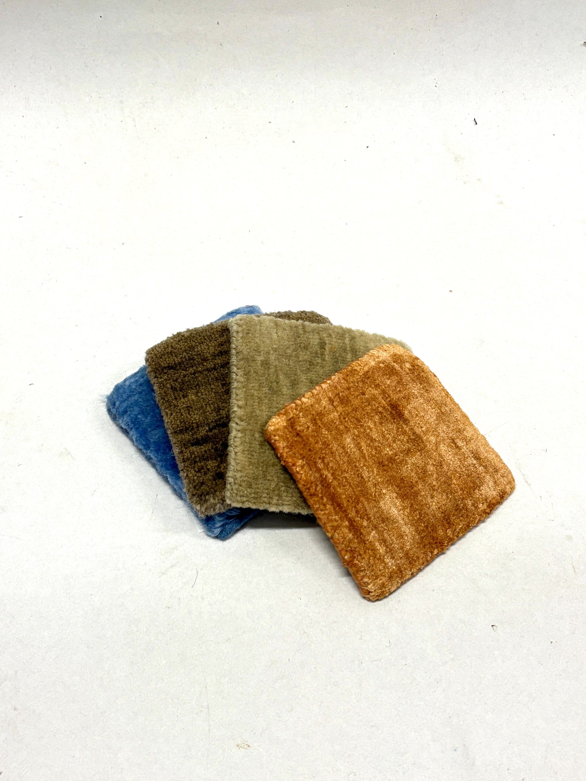 Layered velvet fabric swatches in soft neutral shades on a white background.