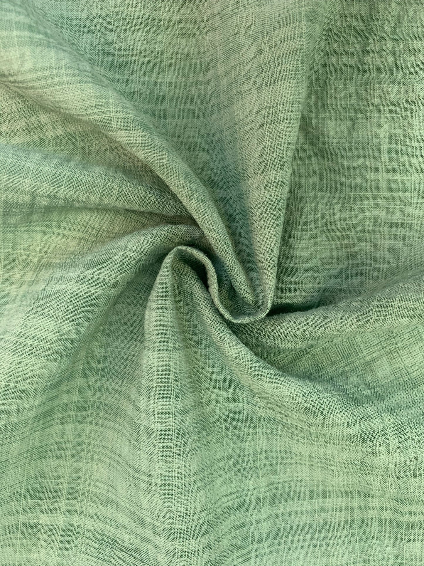 A detailed shot of sage green check fabric with a softly crinkled look.