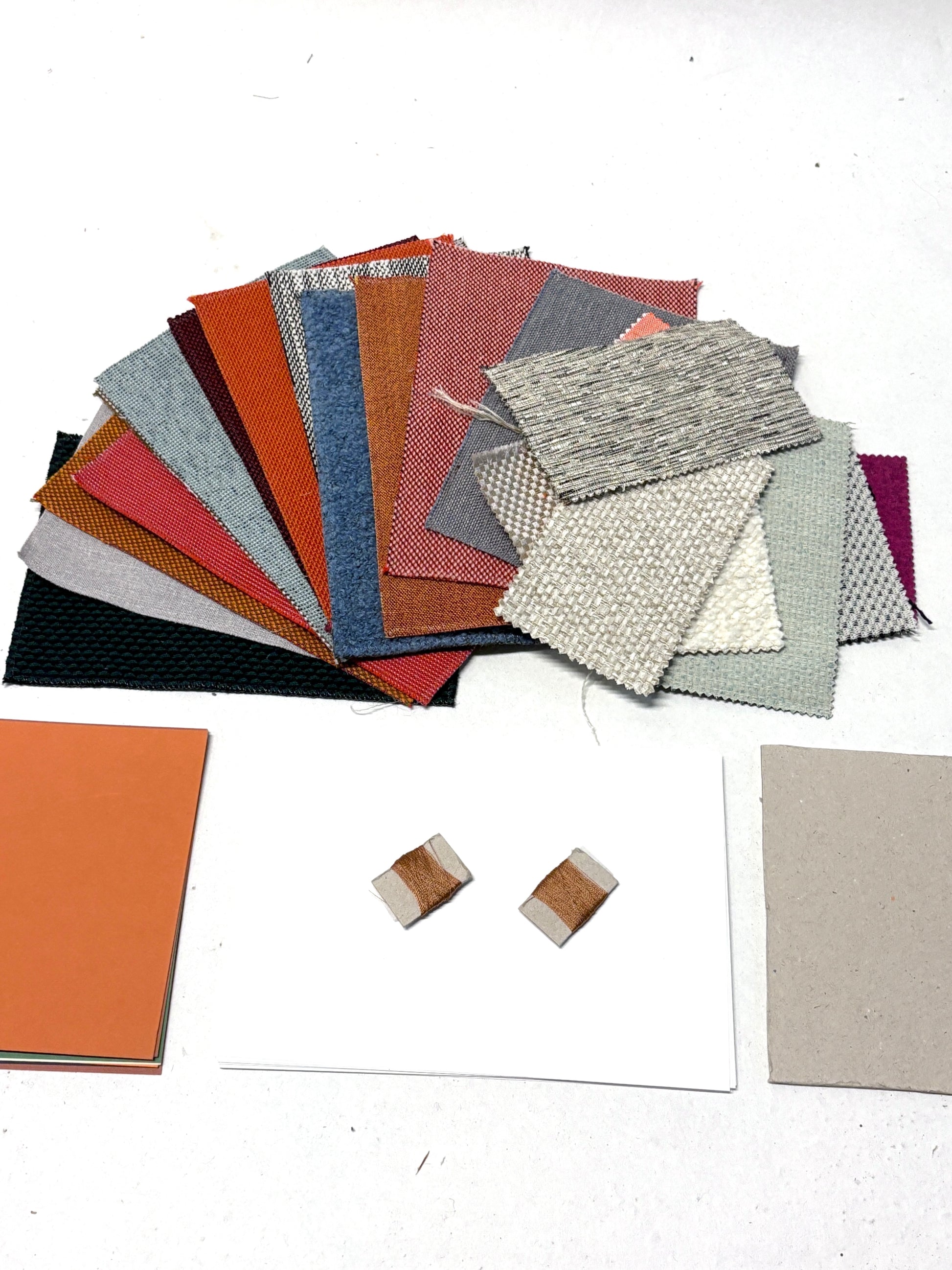 Assorted fabric swatches, sample cards and thread details arranged on a white surface.