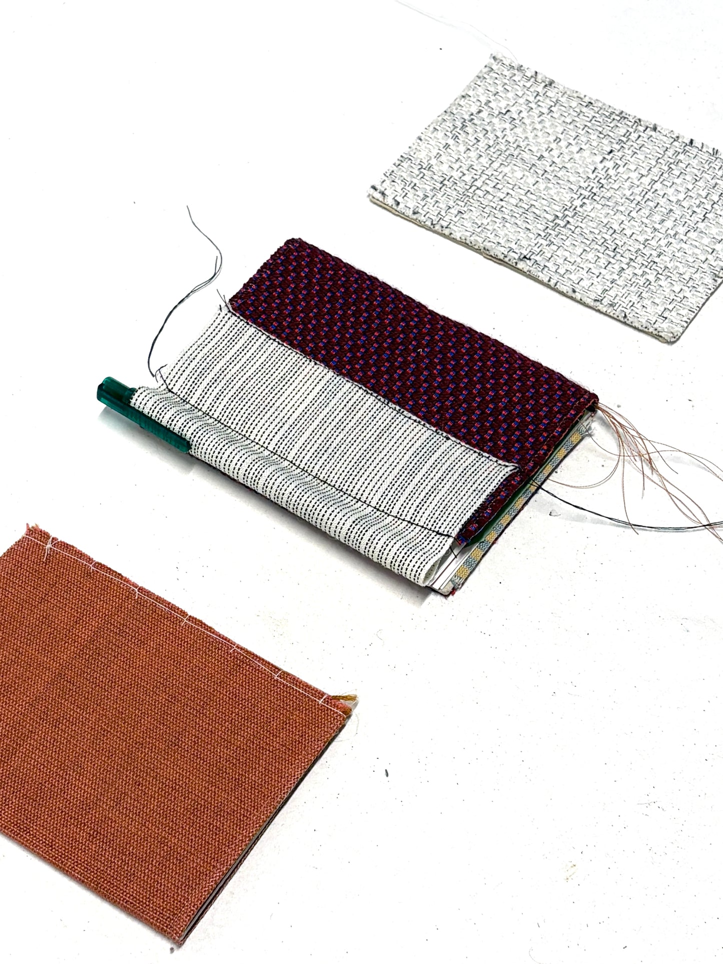 Close-up of handmade notebook samples and fabric-covered booklets on white.
