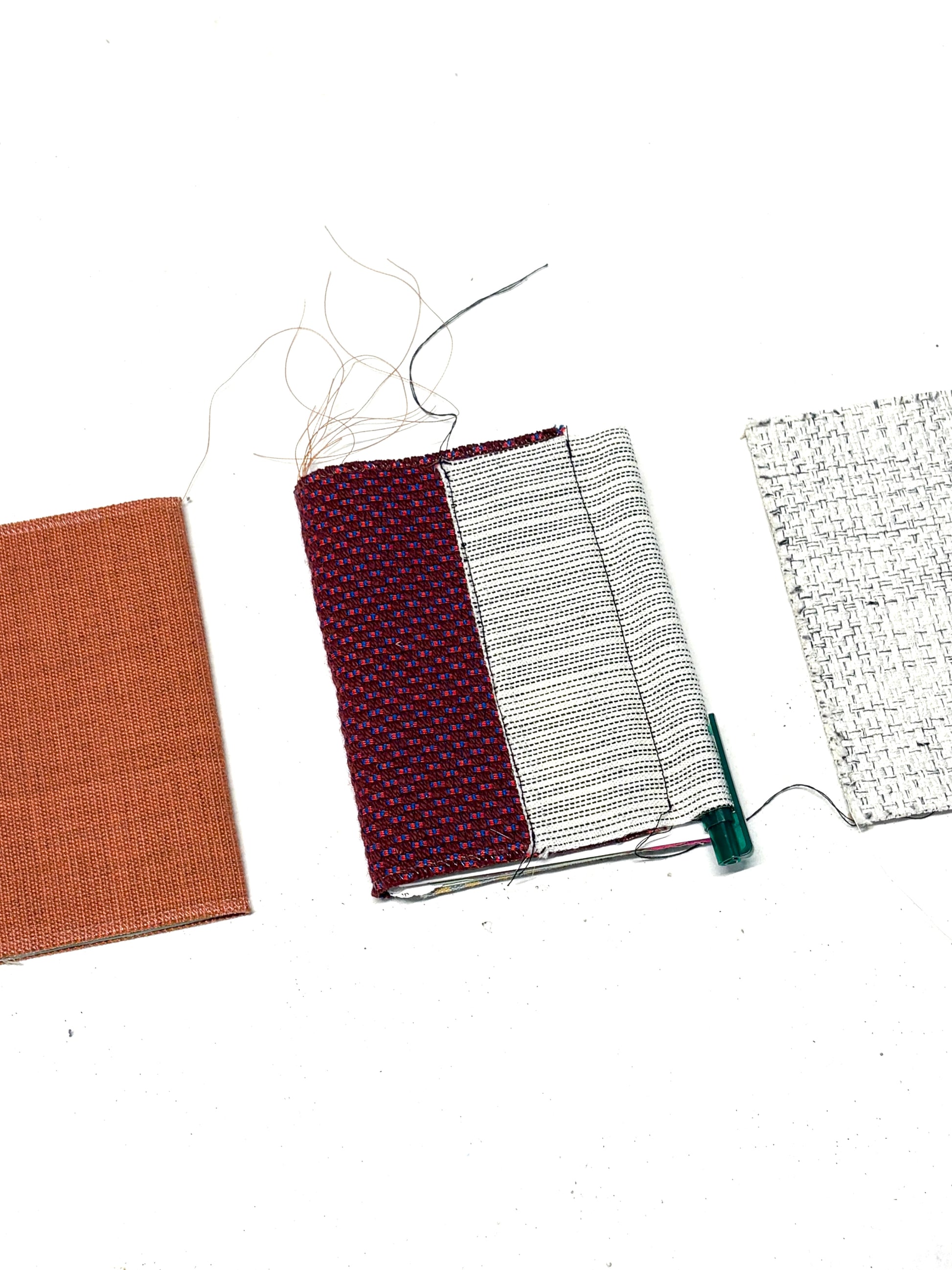 Detailed flat lay of fabric-covered notebook samples and material pieces.