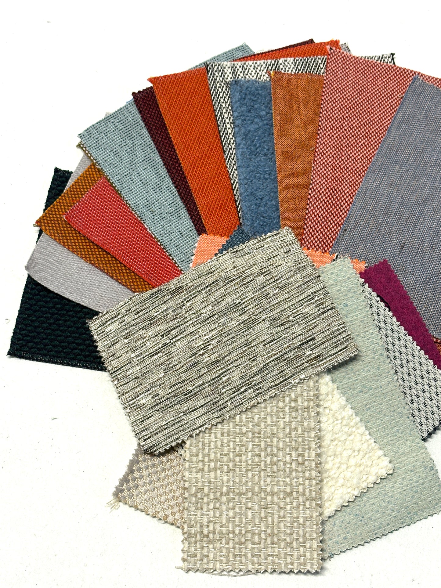 Assorted fabric swatches in varied colours, textures and woven finishes.