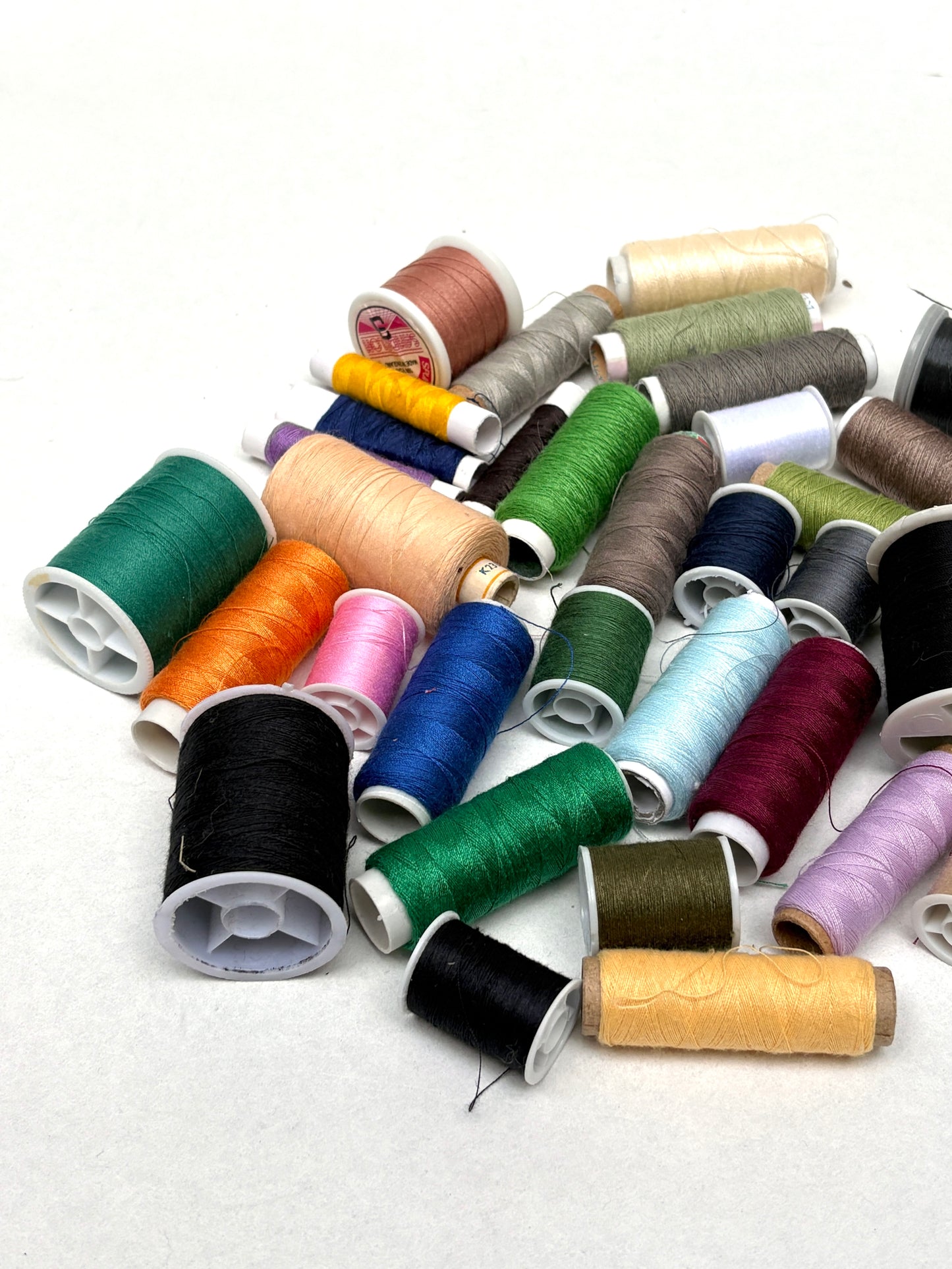 Assorted spools of thread in various colors on a white background