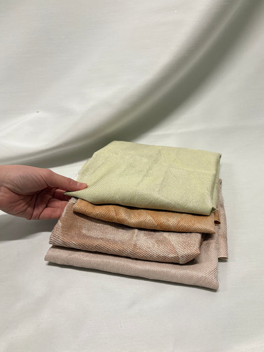 Stack of folded fabric pieces held by a hand on a white surface