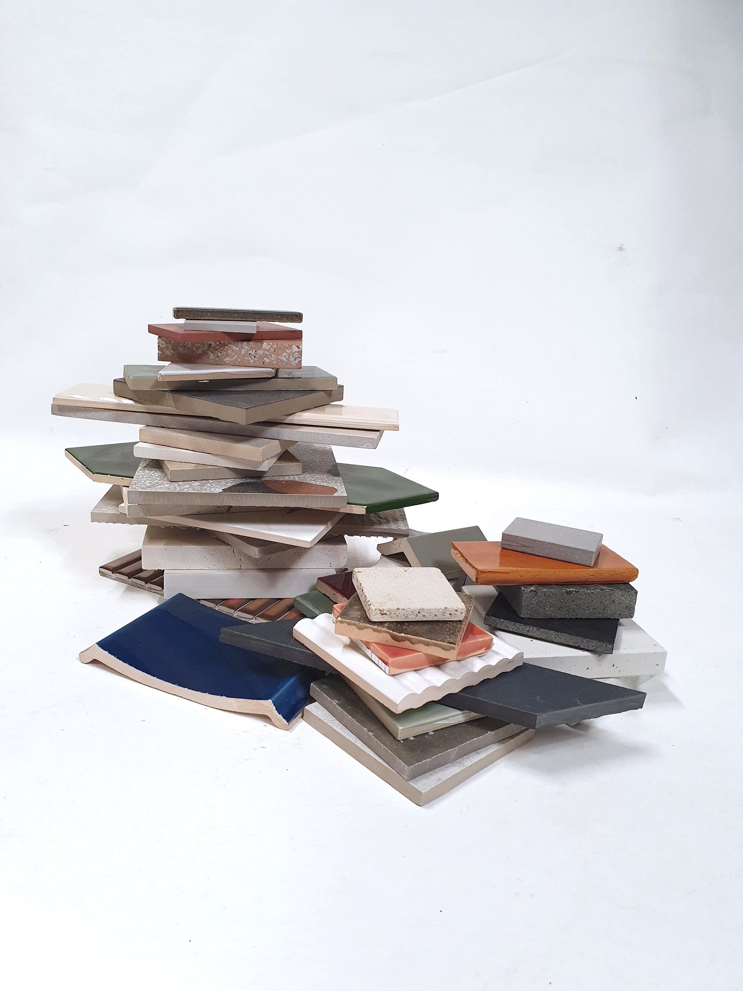 Mixed tile and material samples are stacked on a white background