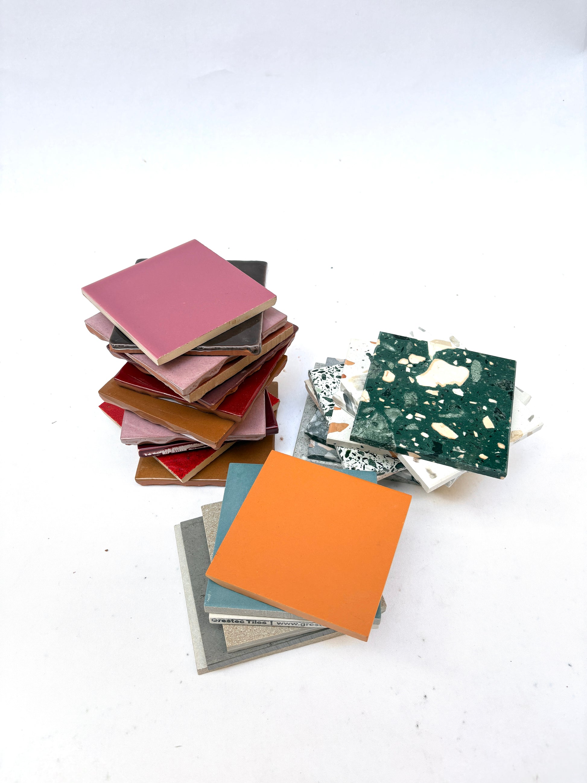 Mixed square tiles are arranged in a small pile on white