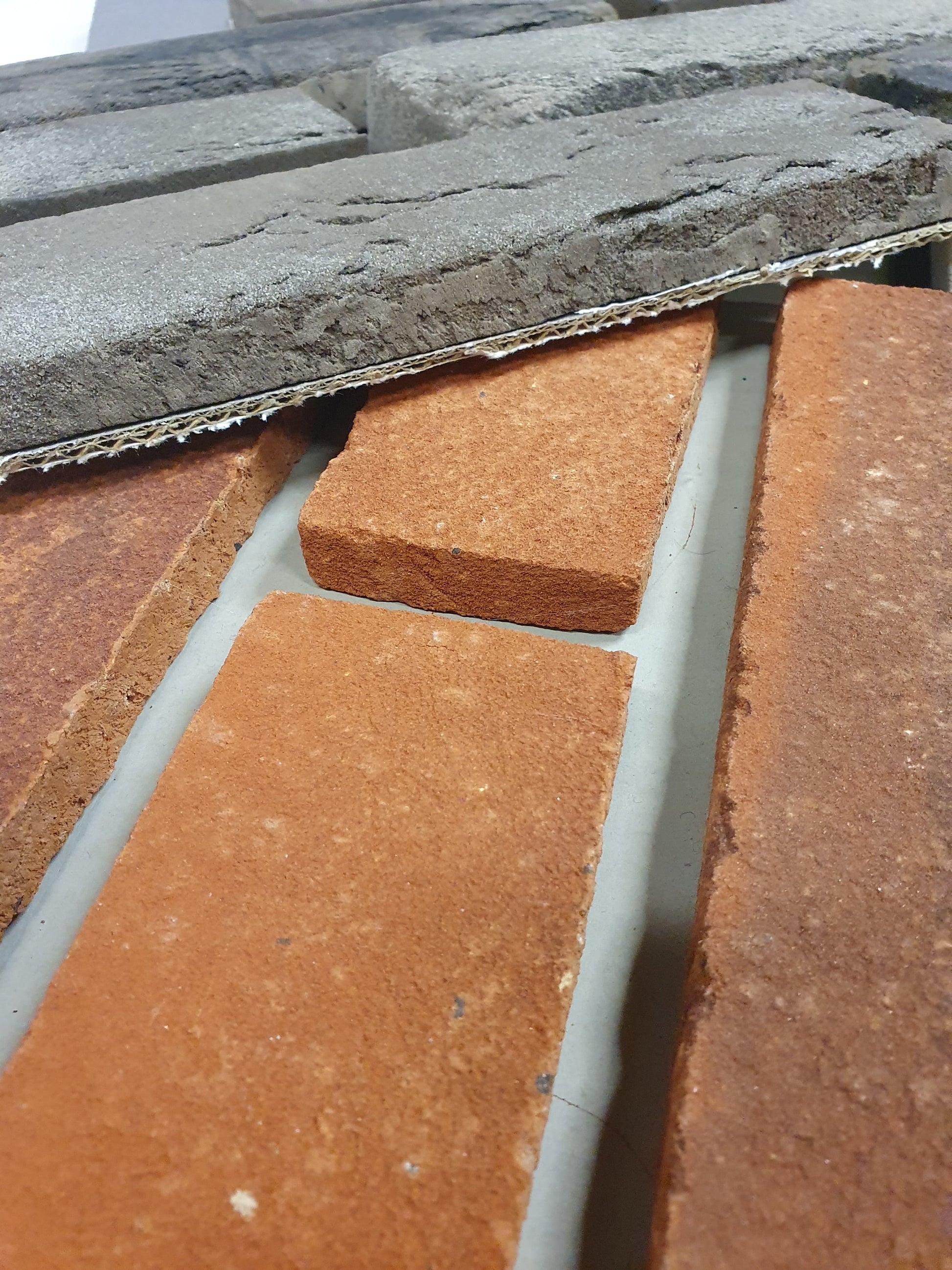 Close-up of brick sample boards in red clay and grey stone tones.