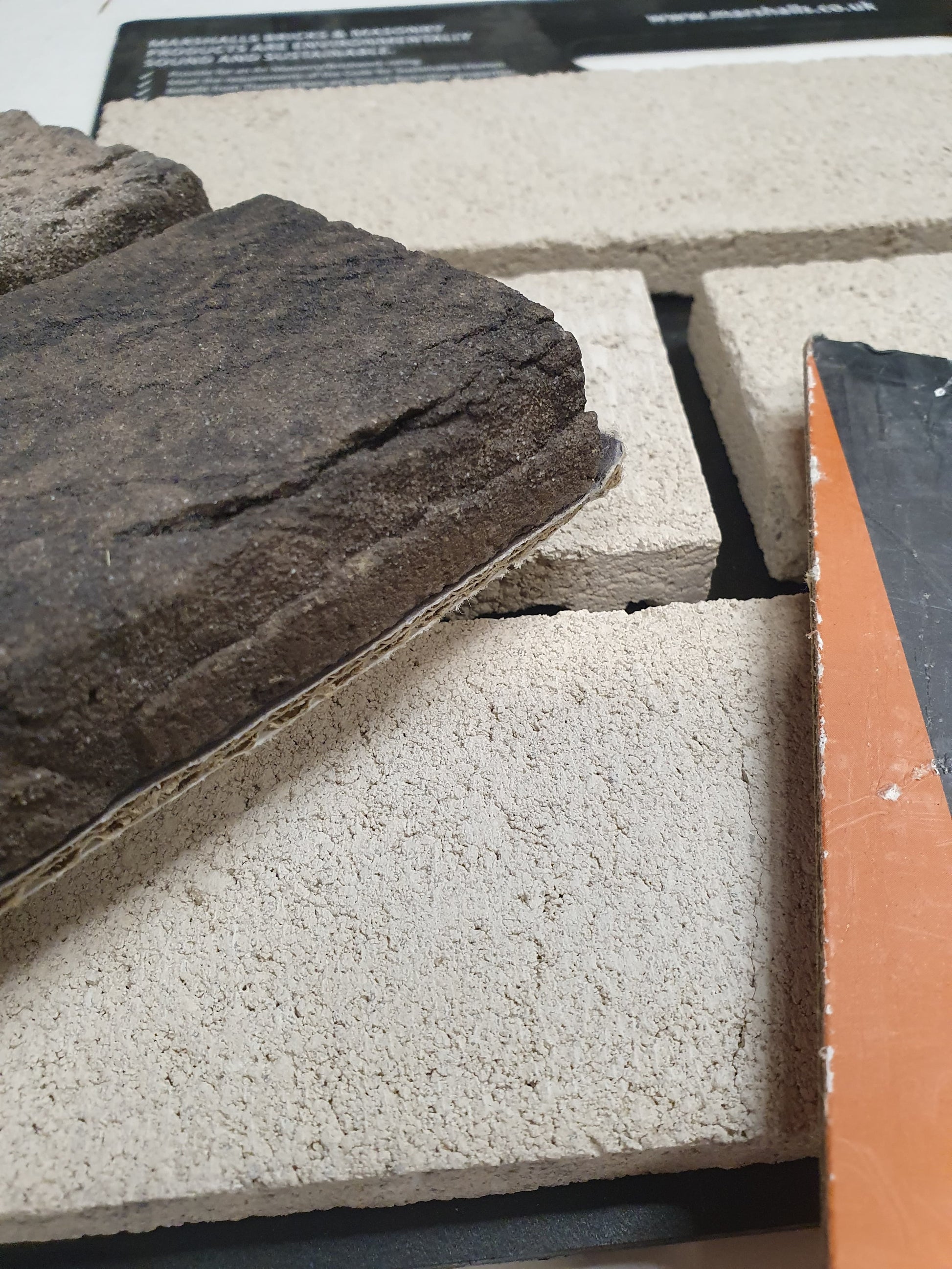 Close-up of textured brick samples in cream and dark stone tones.