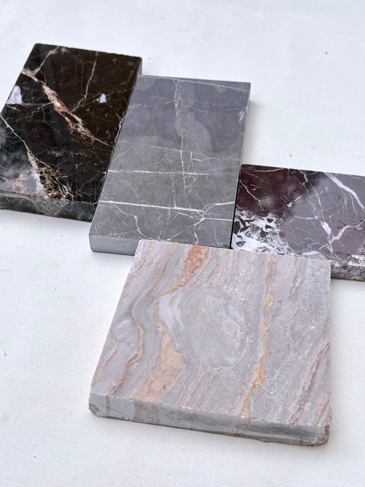 Square sample tiles are arranged in small stacks on a white surface