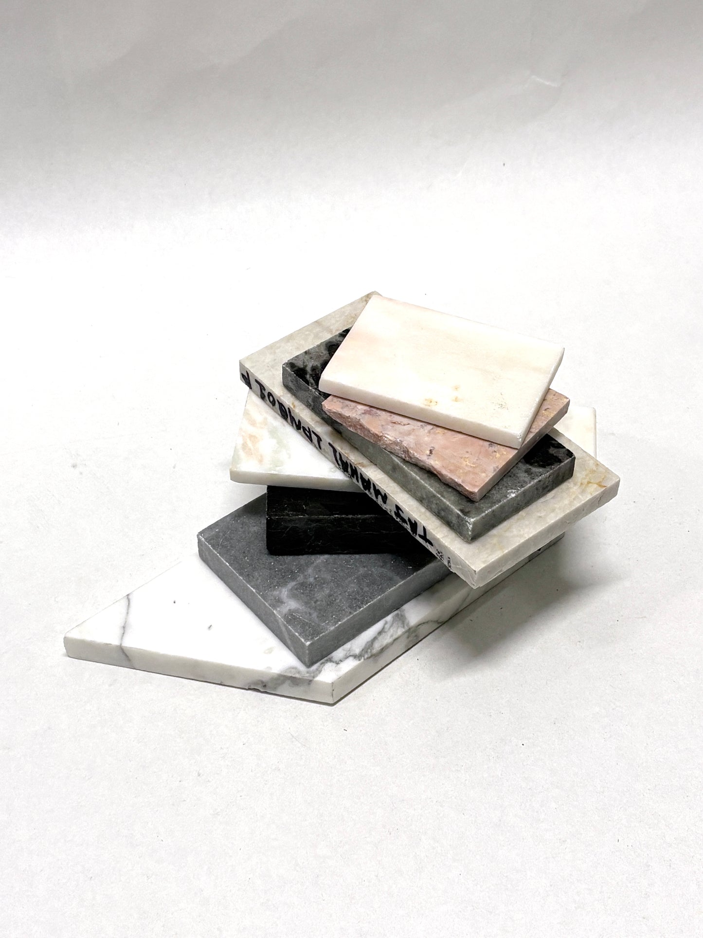 Marble-effect sample tiles are stacked on a white background