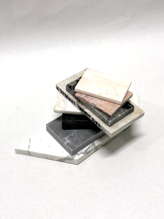 Marble-effect sample tiles are stacked on a white background