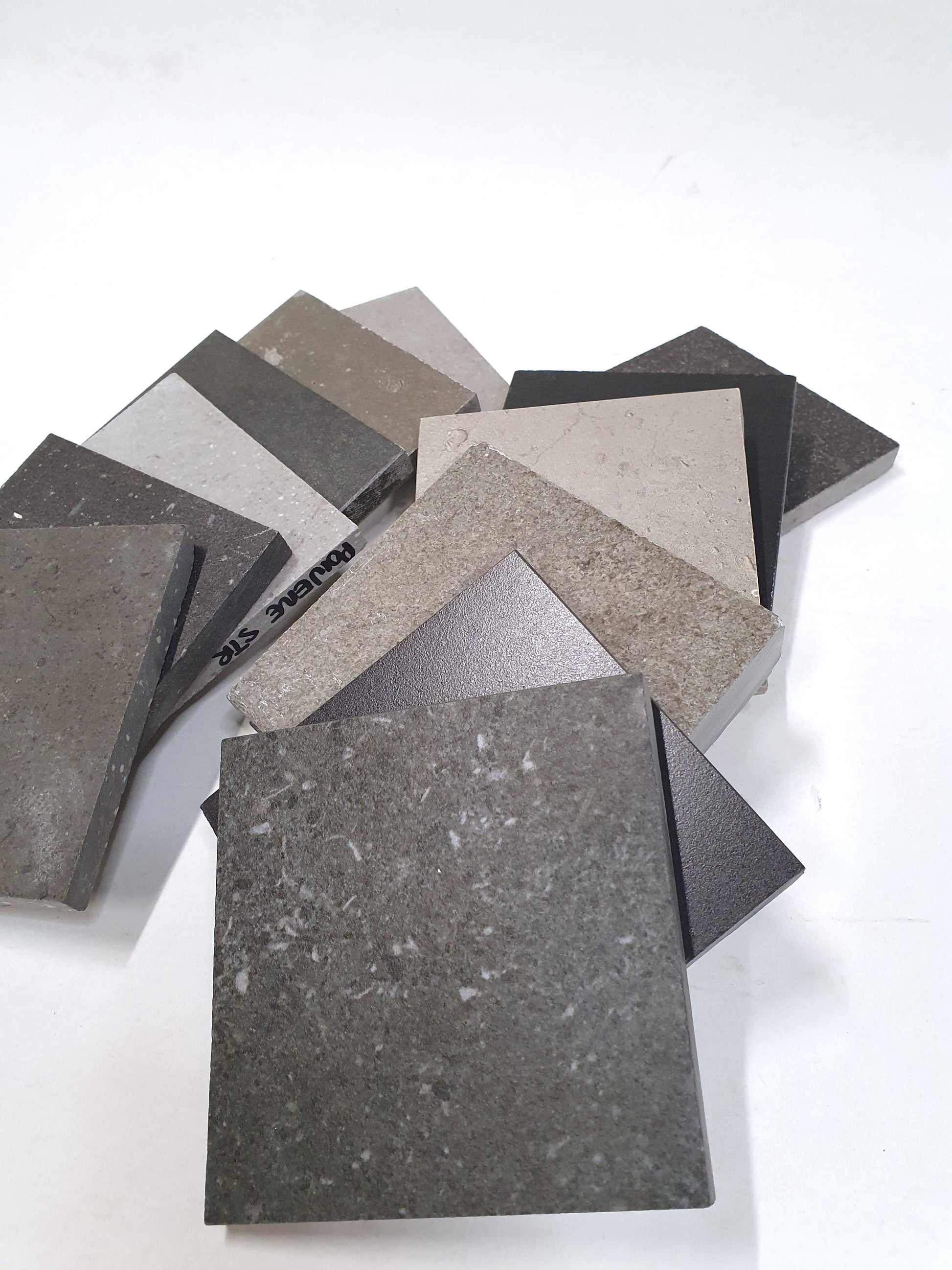 Assorted grey tile samples arranged on a white background.