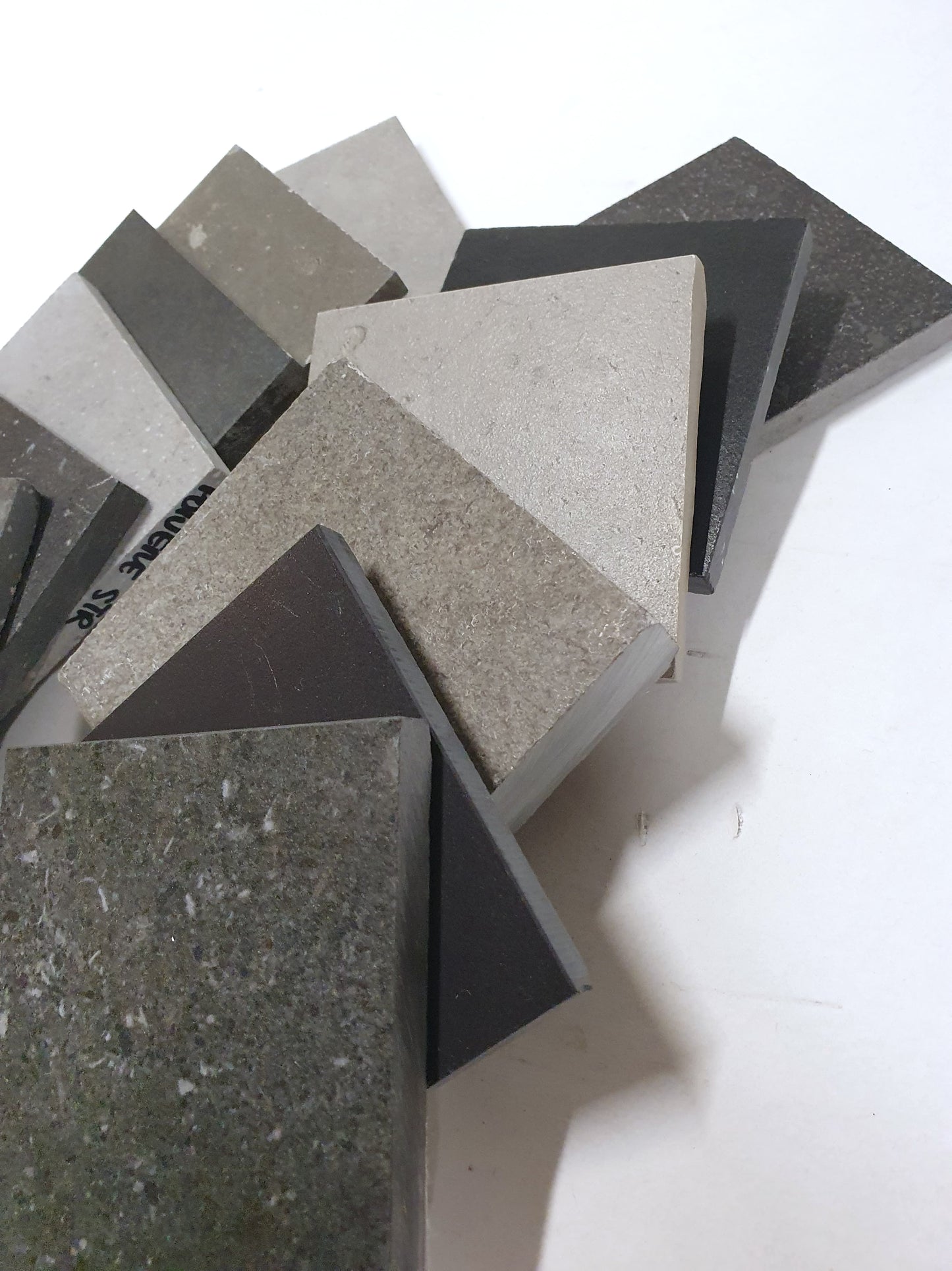 Mixed grey tile samples layered on a white background.