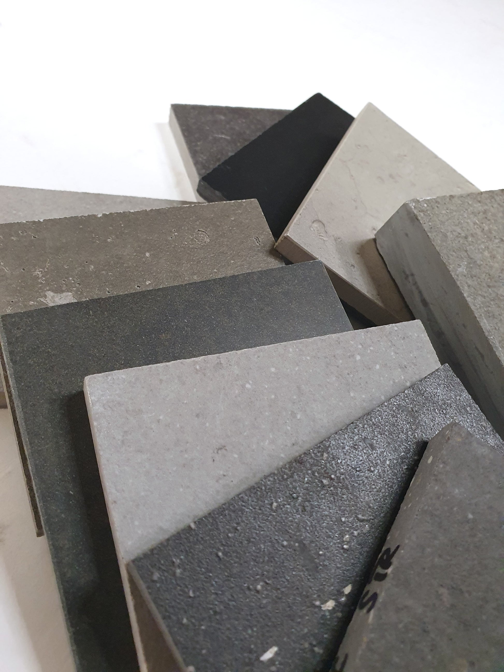 Close-up of layered grey tile samples in assorted stone-like finishes.