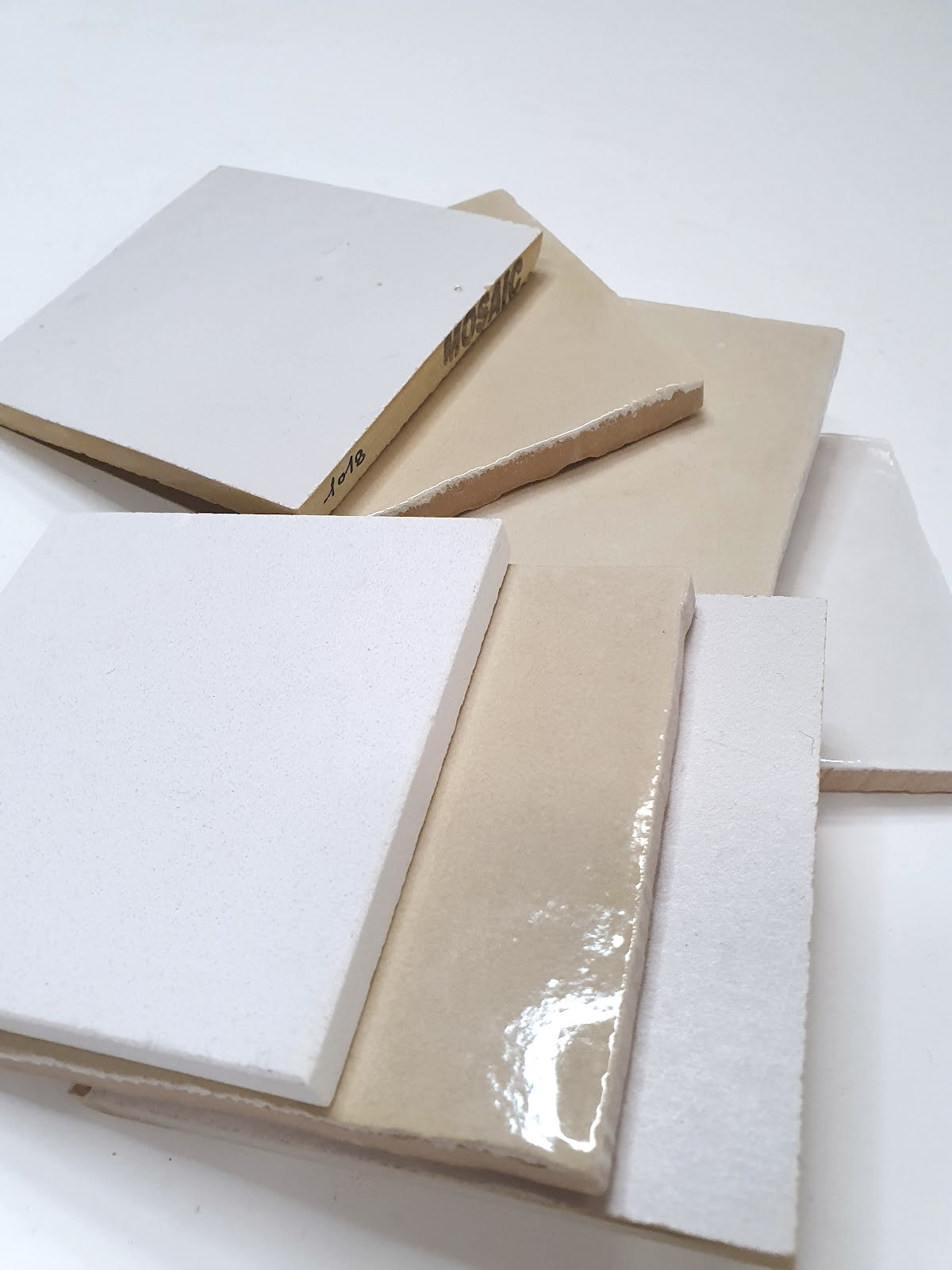 Close-up view shows layered white sample tiles with glossy surfaces