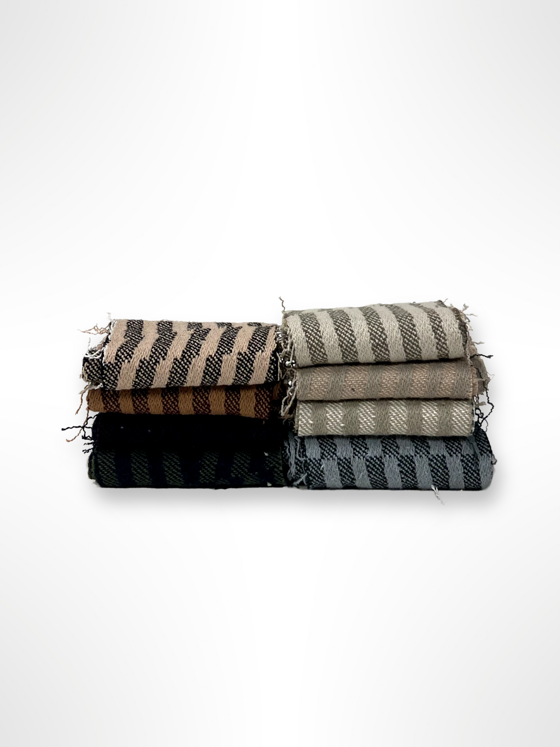Folded striped fabric pieces are stacked on a white background